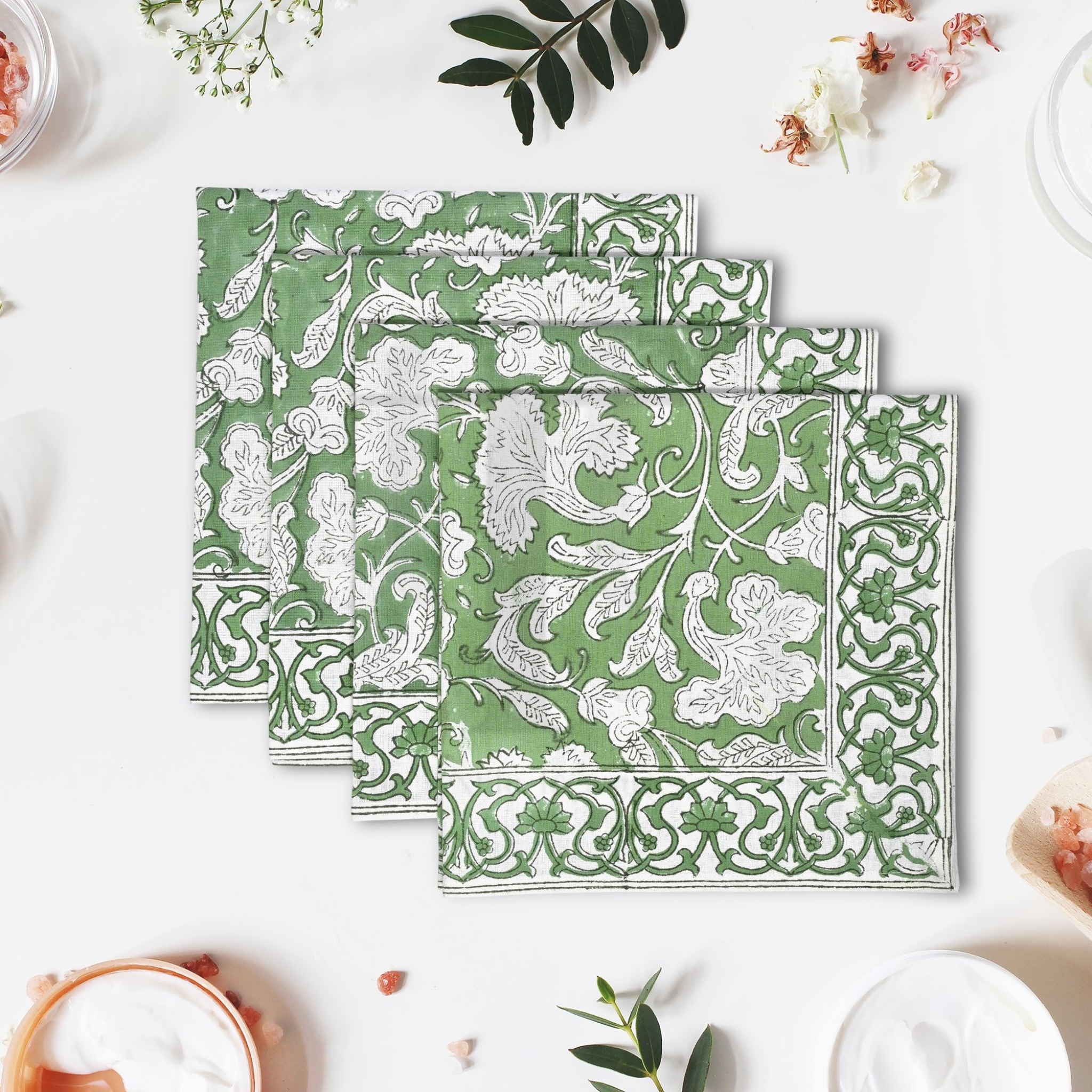 Set of green and white patterned napkins on a white surface with decorative elements.