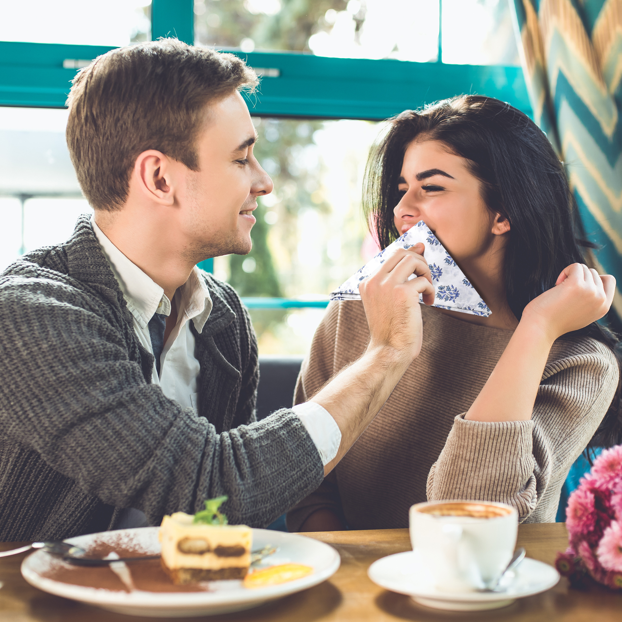 Man and woman sharing a moment at a cafe with a cup of coffee and cake.