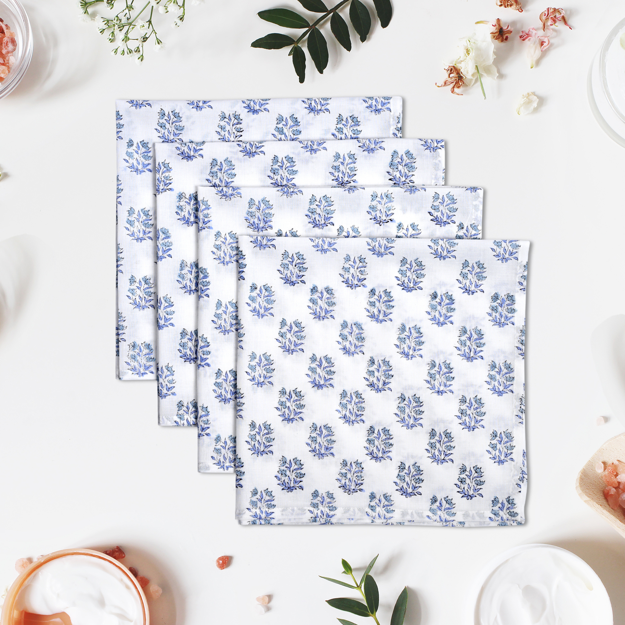 Set of three blue floral patterned napkins on a white surface with decorative elements.