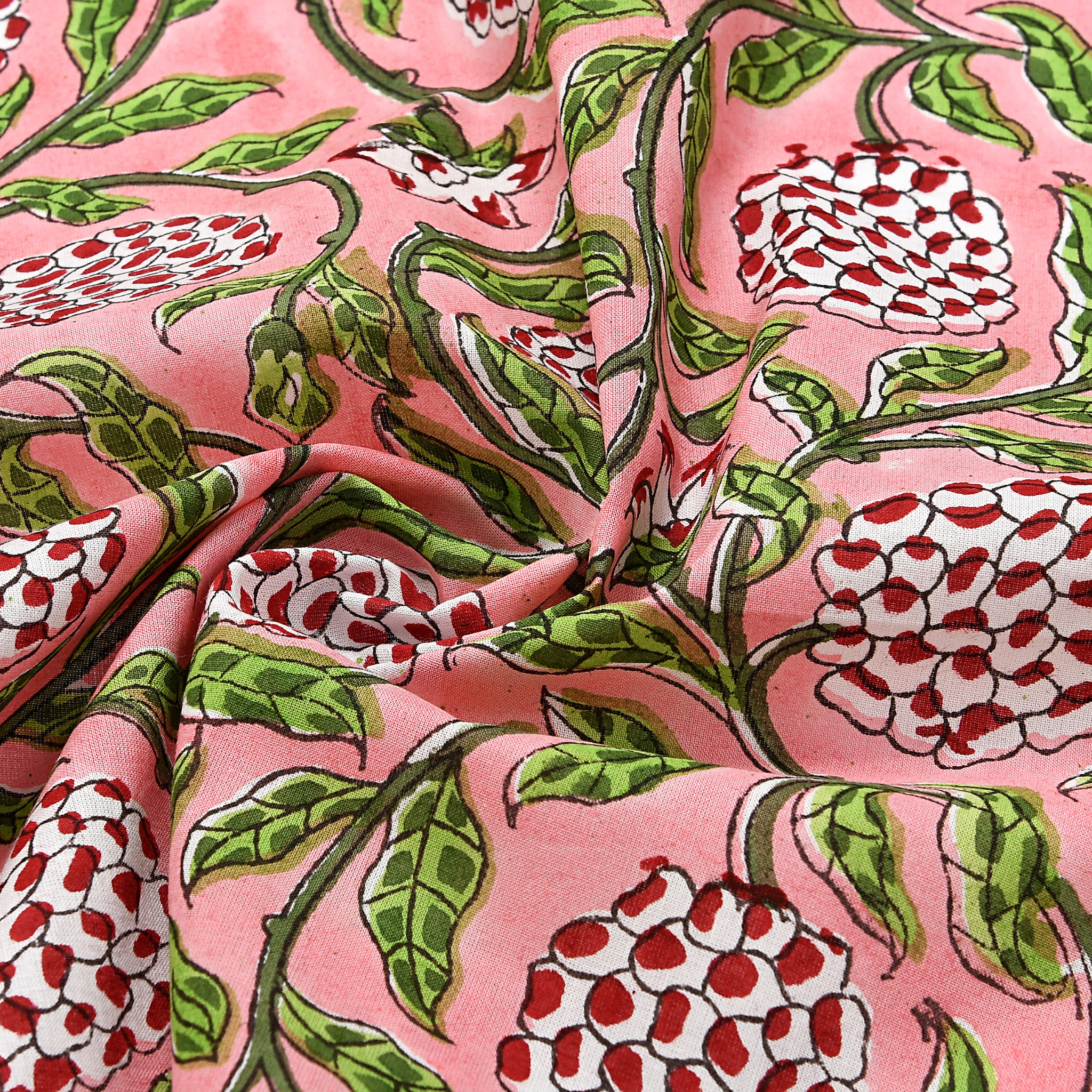Floral patterned fabric with red and white flowers on a pink background