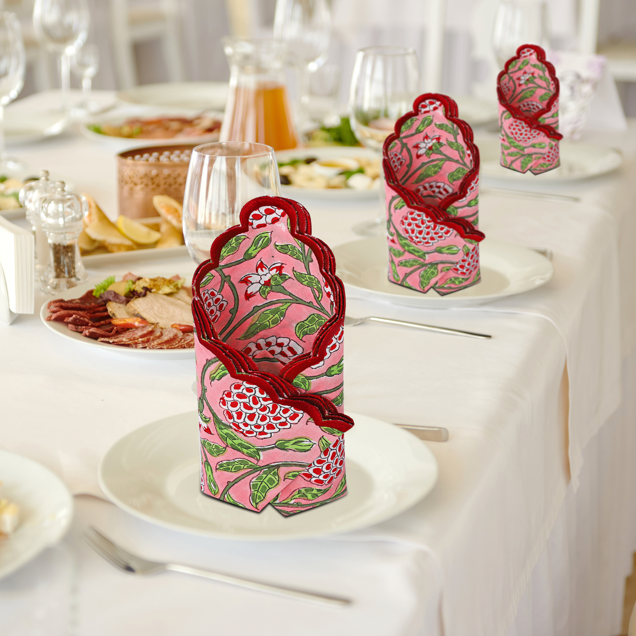 Decorative pink and green bottle cover on a wine bottle with a table setting in the background.