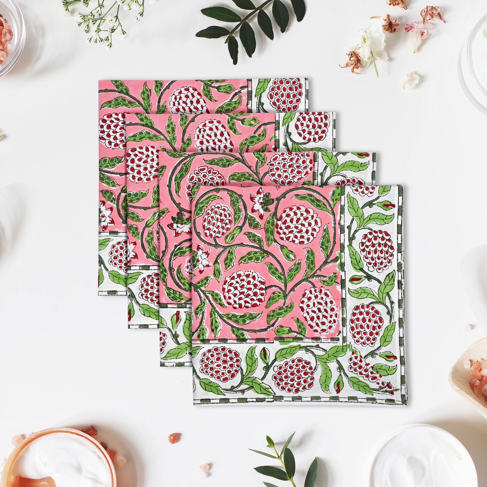 Set of three pink and green patterned napkins on a white surface with decorative elements.