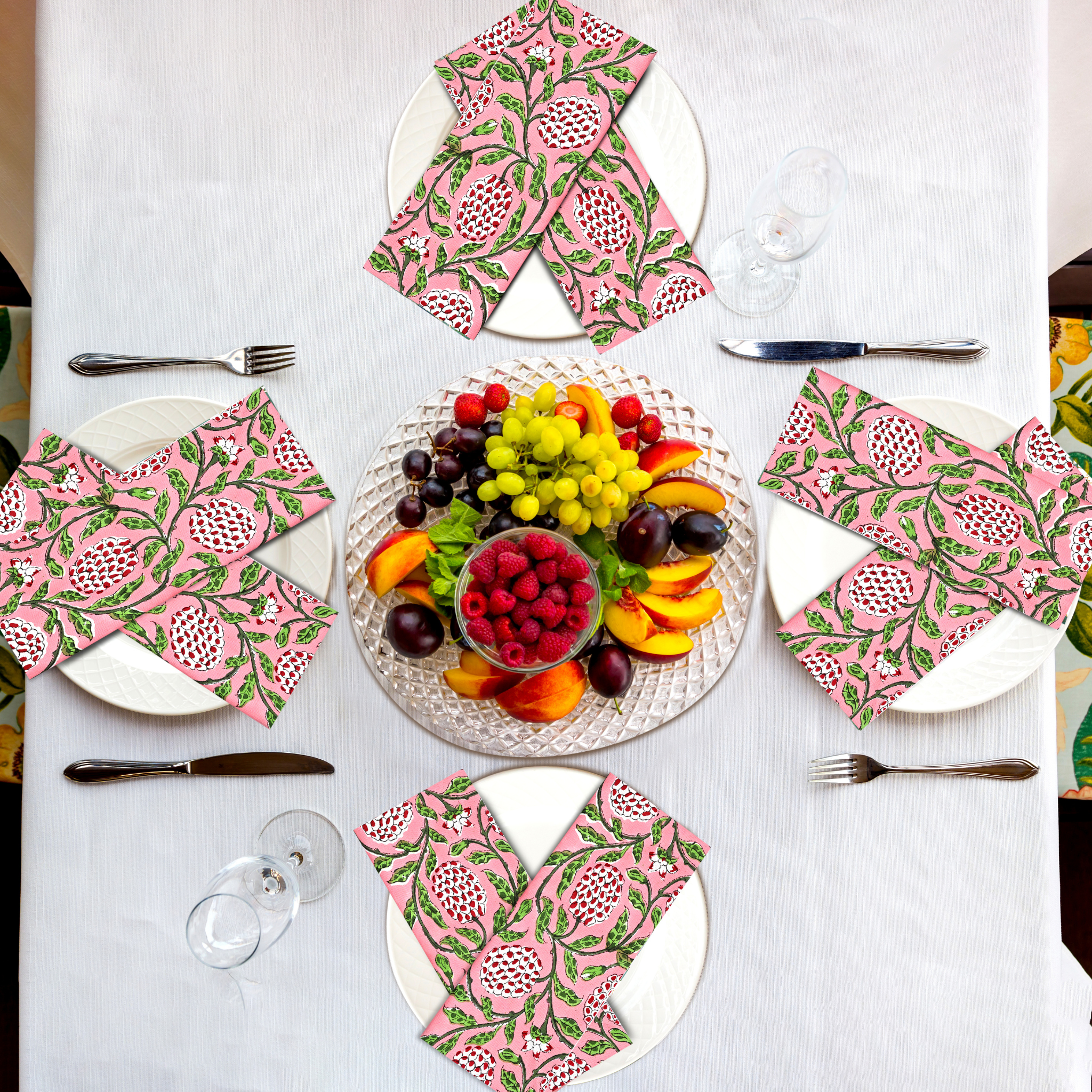 Table setting with pink and green patterned napkins and a fruit platter.