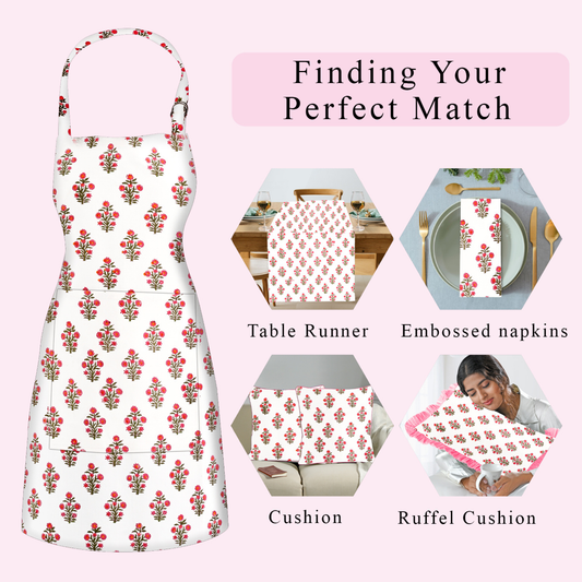 Floral apron with matching table runner, napkins, cushion, and ruffel cushion on a pink background.