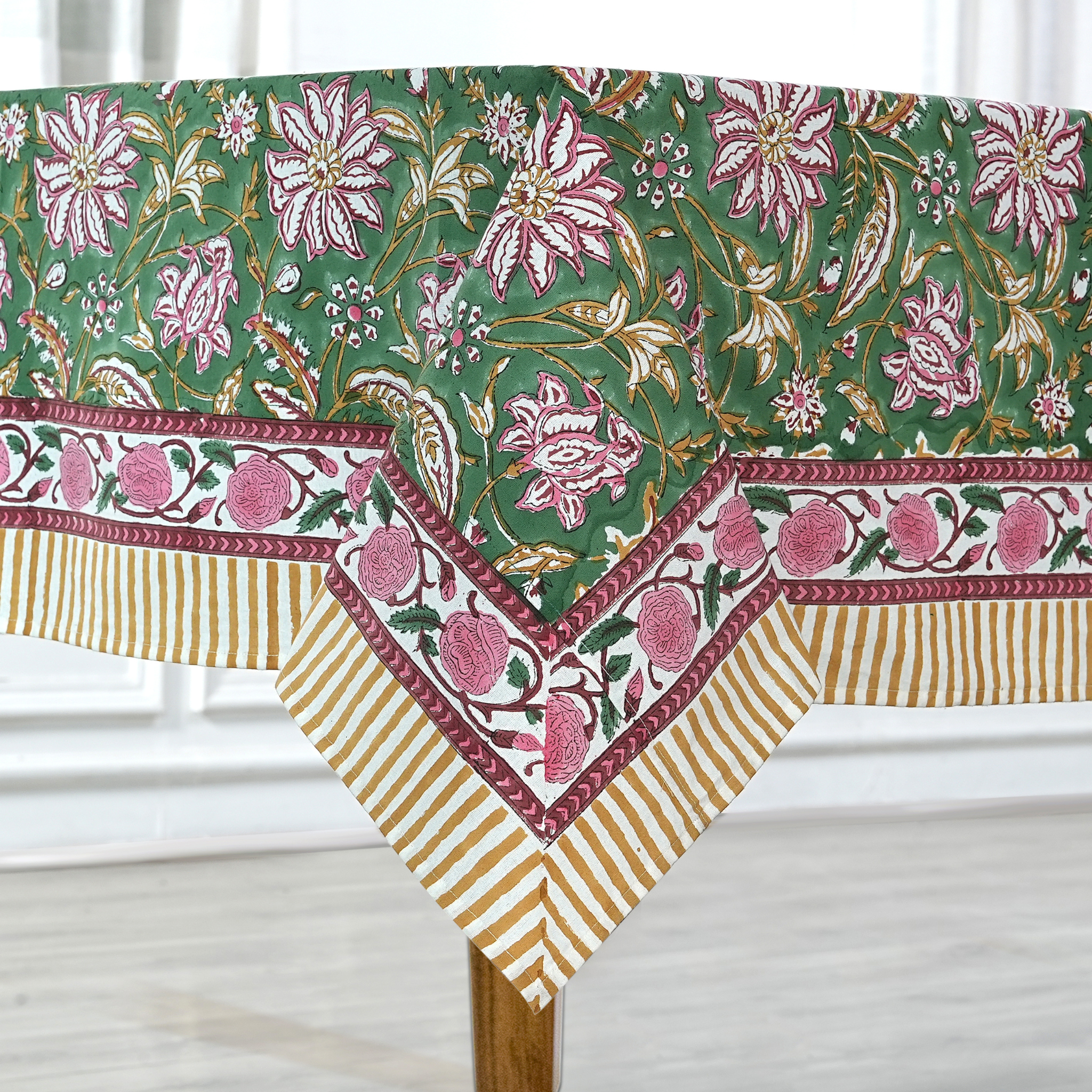 Decorative tablecloth with floral and striped pattern on a wooden table.