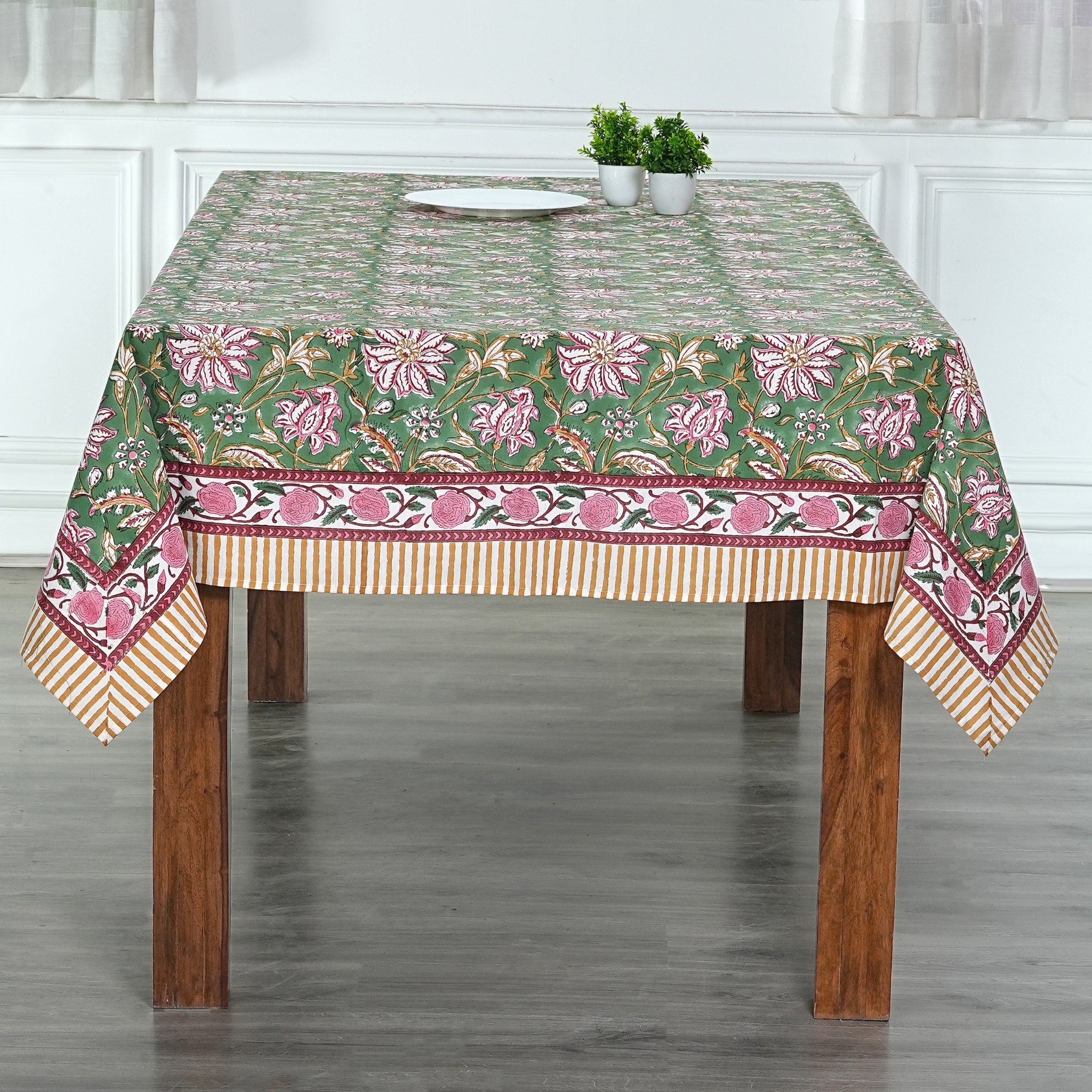Tablecloth with floral pattern on a wooden table in a room.
