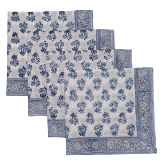 Set of four blue and white patterned placemats on a white background