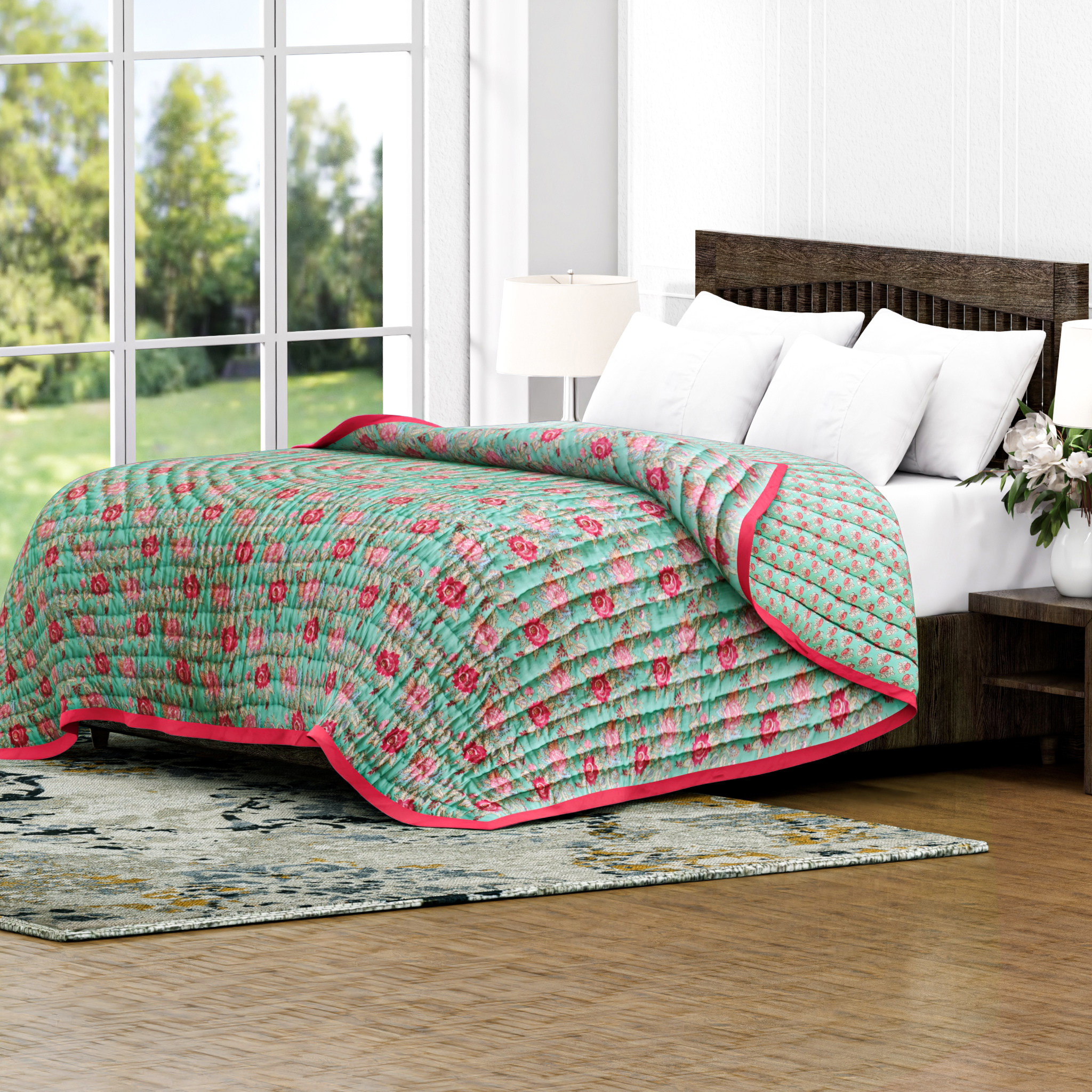 Bed with a green and pink floral quilt in a bright room with large windows.