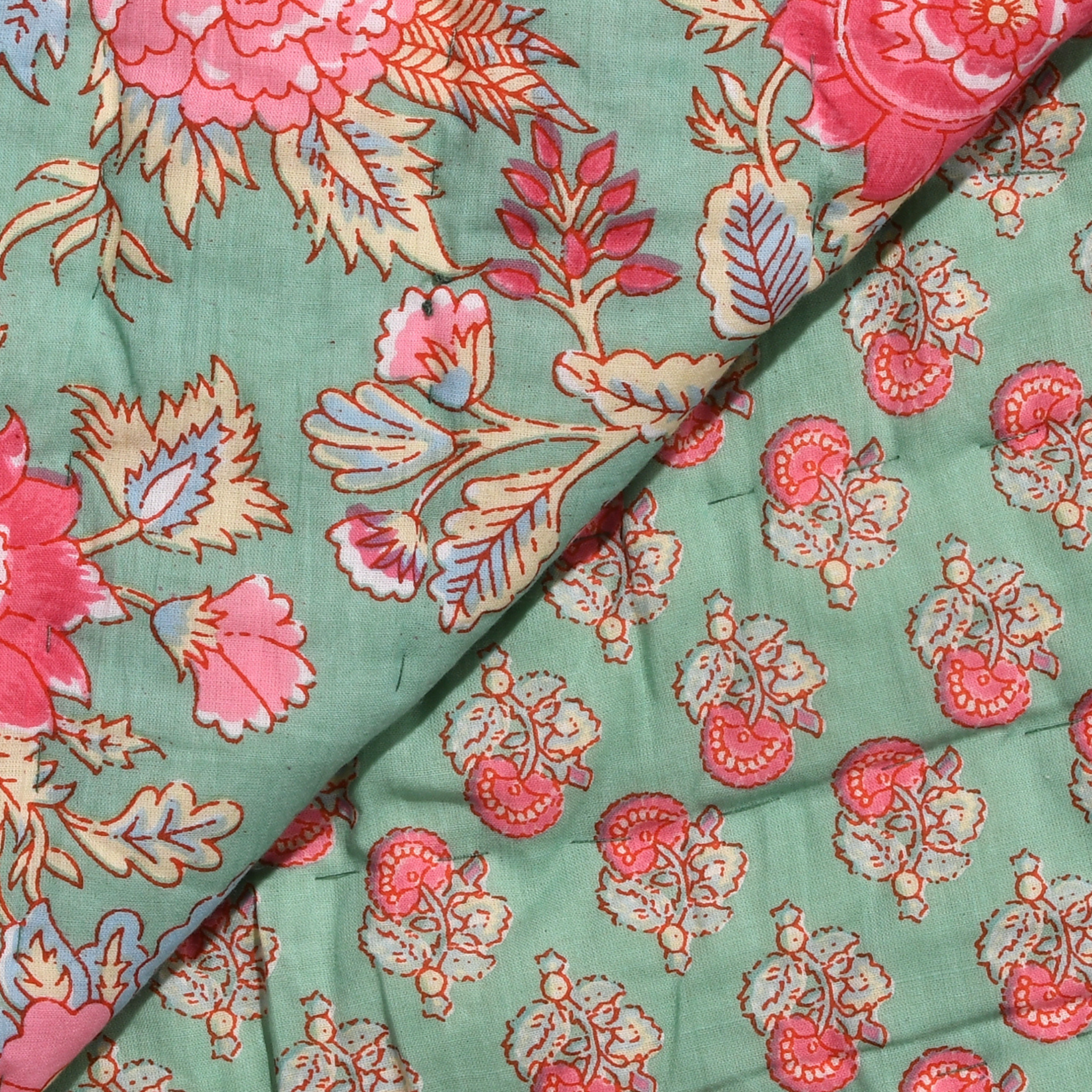 Floral fabric pattern with pink and red flowers on a green background