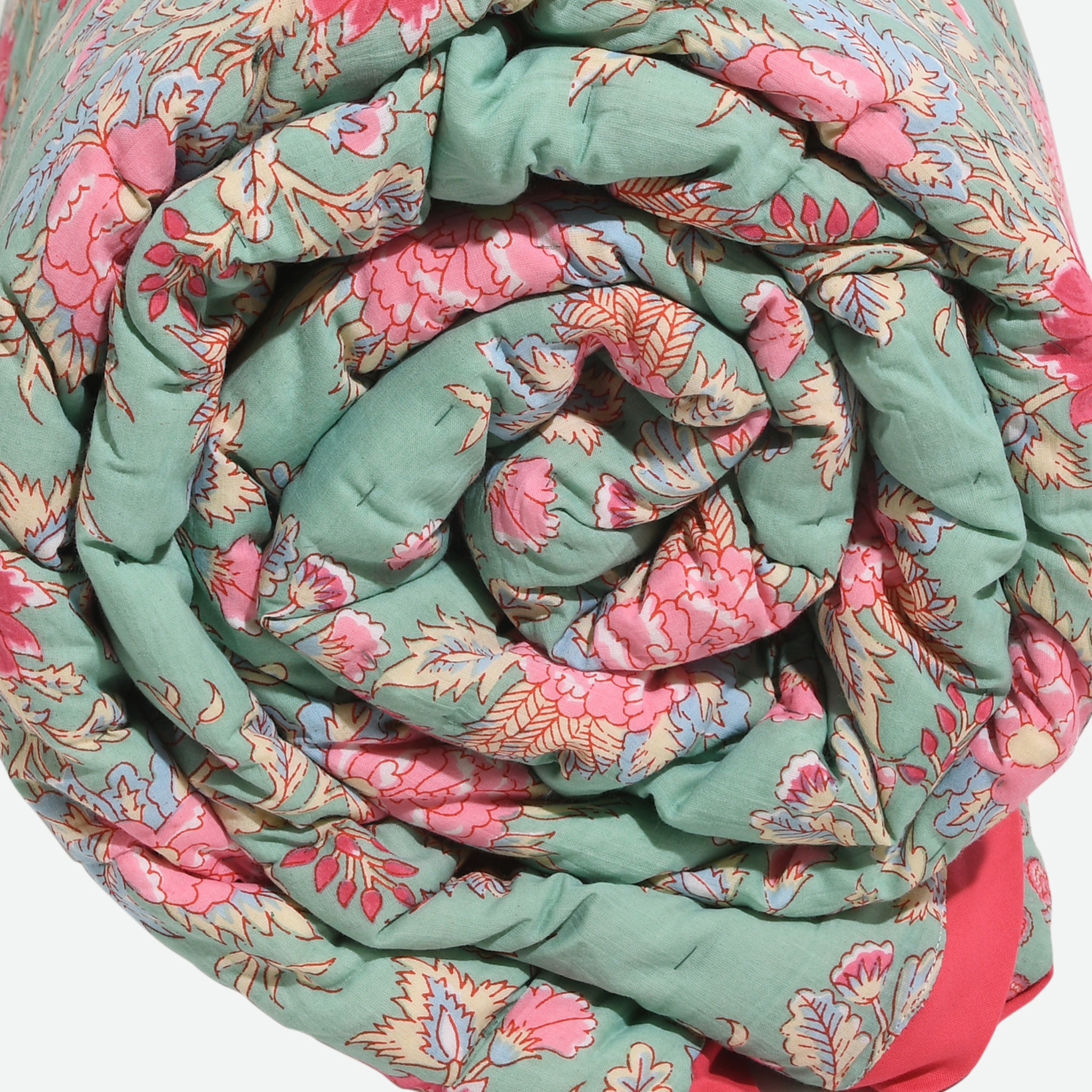 Rolled-up floral quilt with pink and green colors on a white background