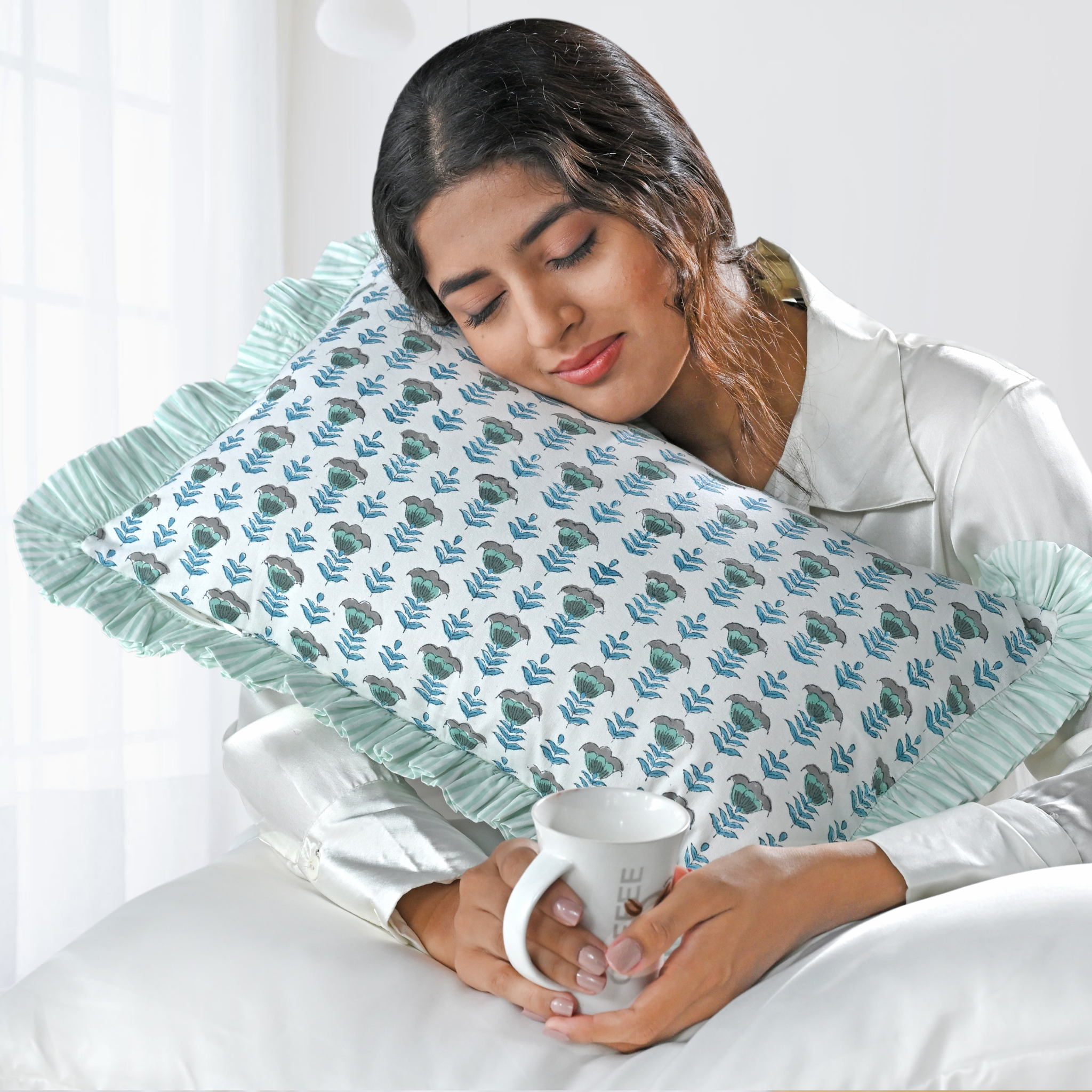 Woman holding a mug with a decorative pillow featuring leaf patterns.