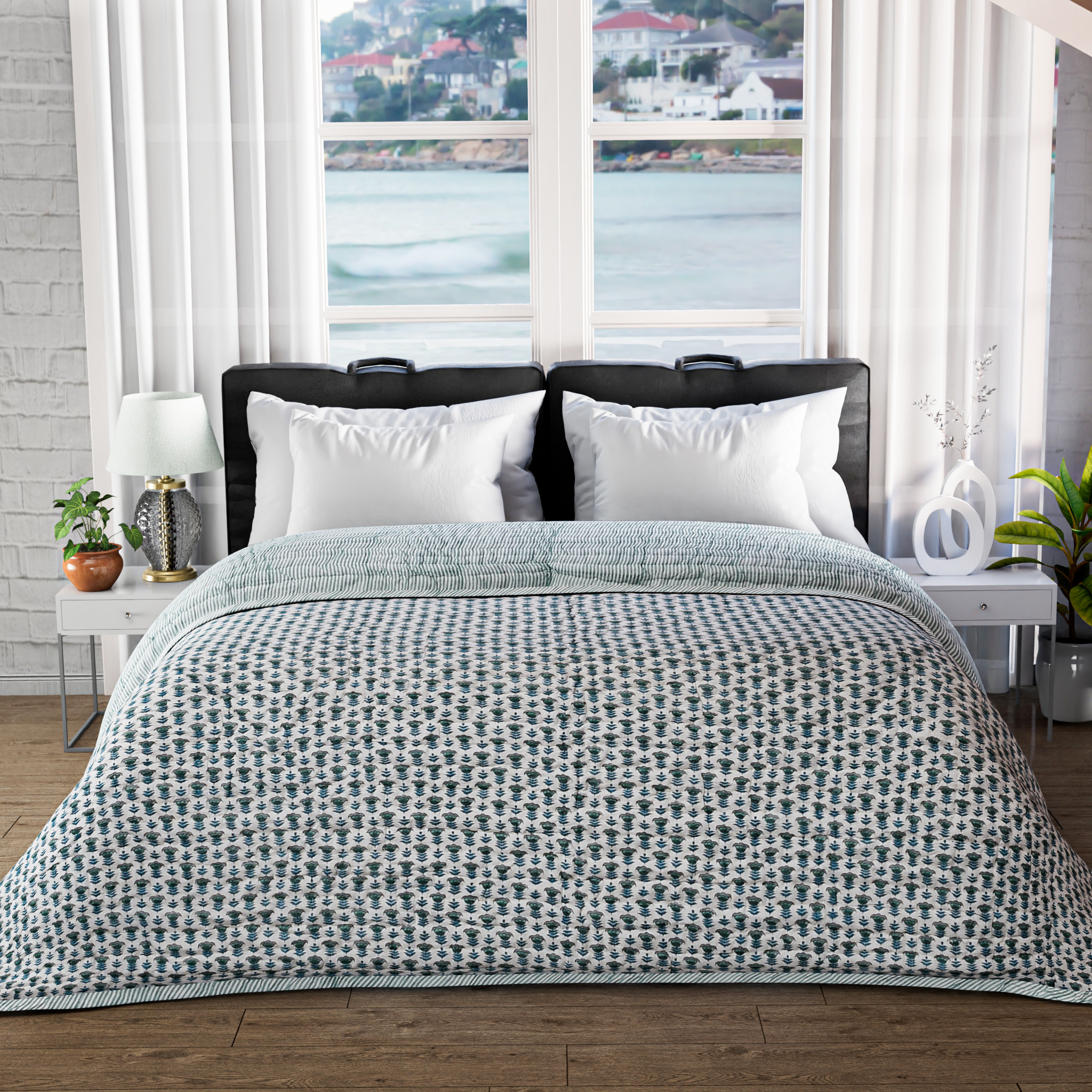 Bed with patterned comforter in a room with large windows showing a waterfront view.