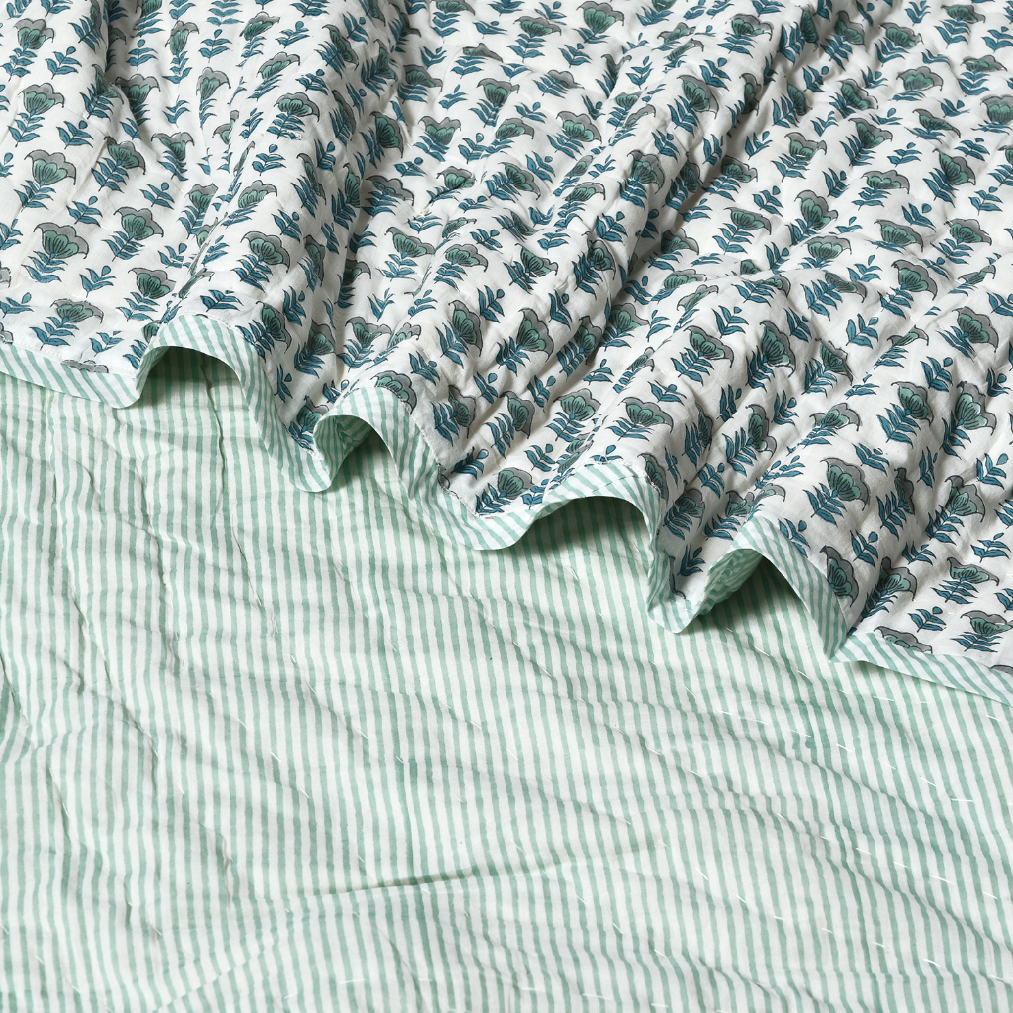 Close-up of a green and white striped fabric with a floral pattern on top