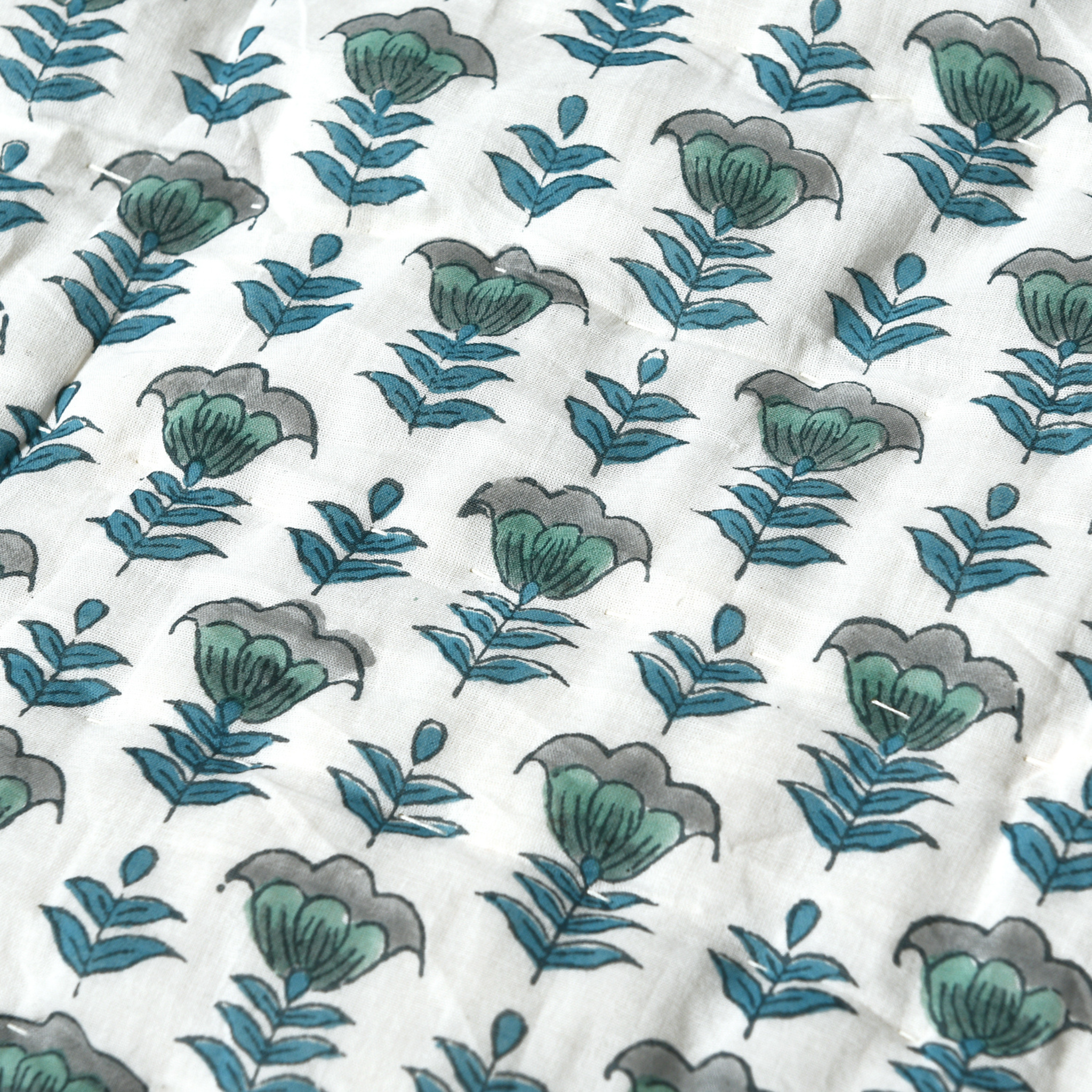 Patterned fabric with green and gray leaves on a white background