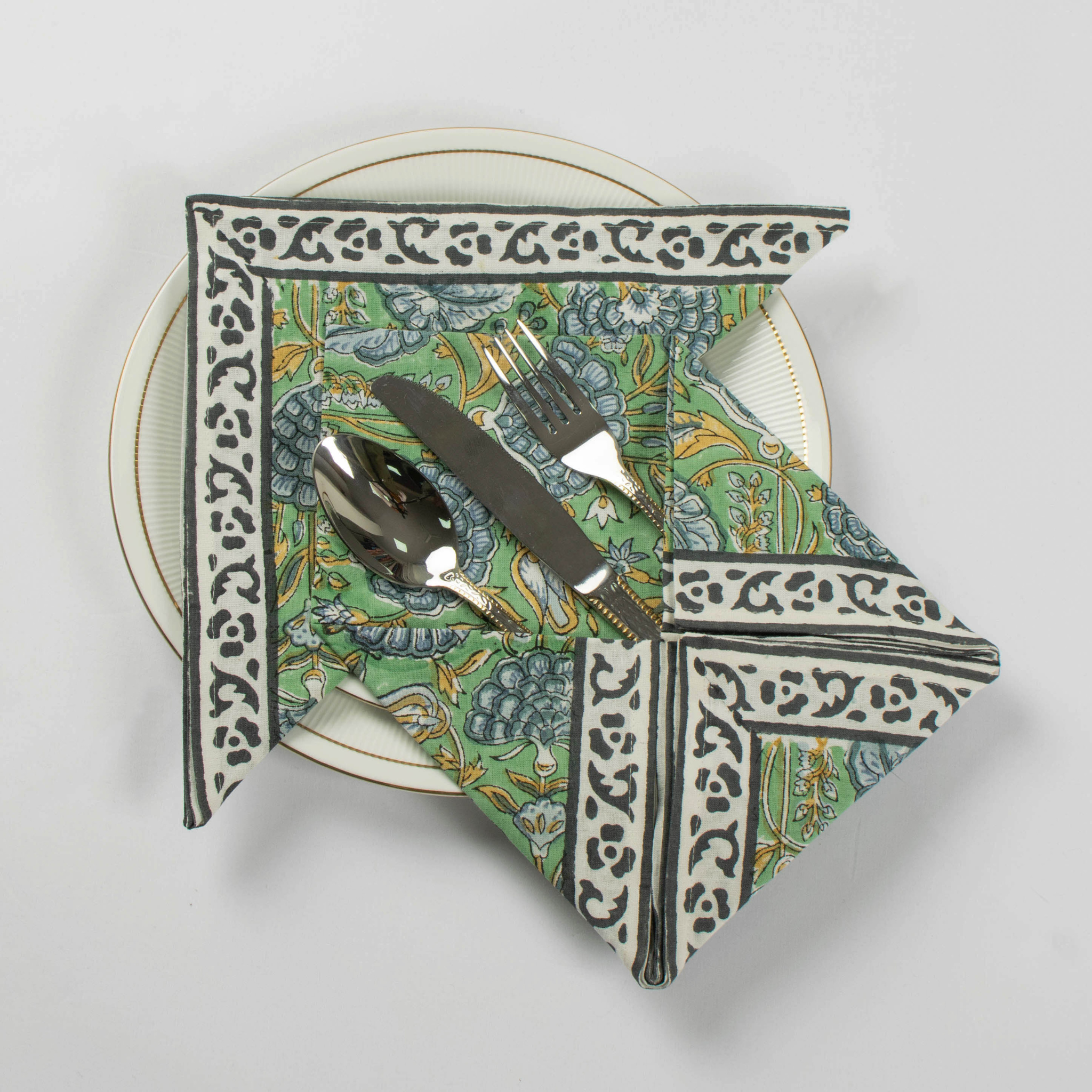 Decorative folded napkin with a pattern on a white plate with cutlery