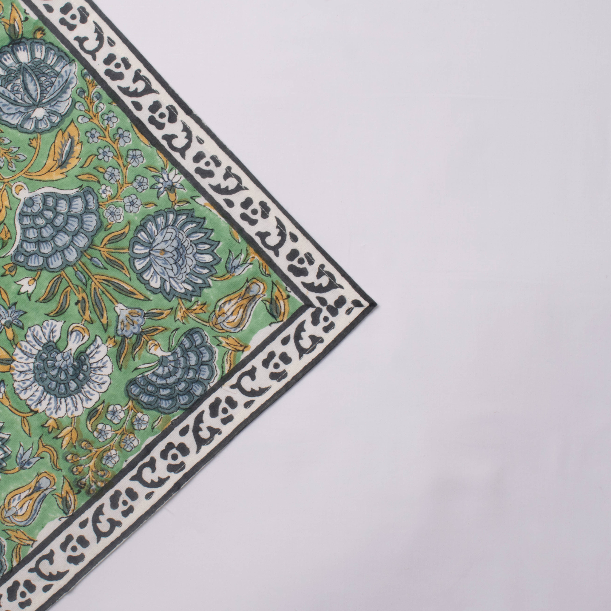 Corner of a fabric with intricate floral pattern on a white background