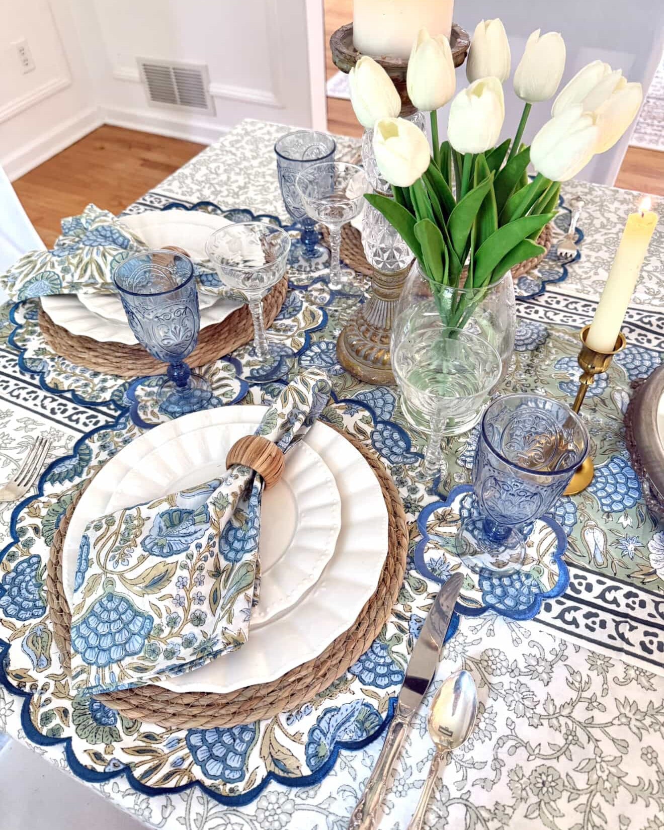 Elegant table setting with blue and white decor, white tulips, and decorative plates.