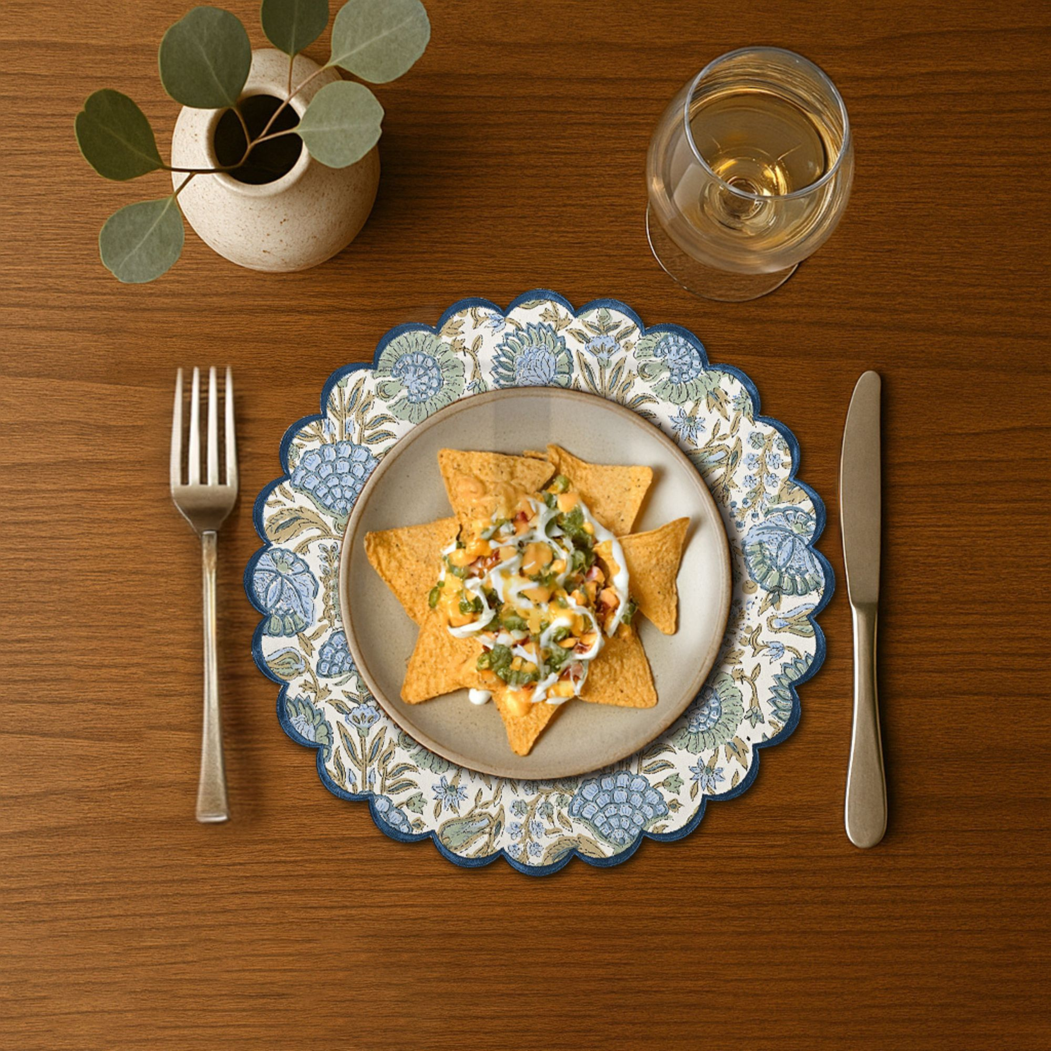 Dinner setting with a plate of food, fork, knife, and glass on a wooden table.