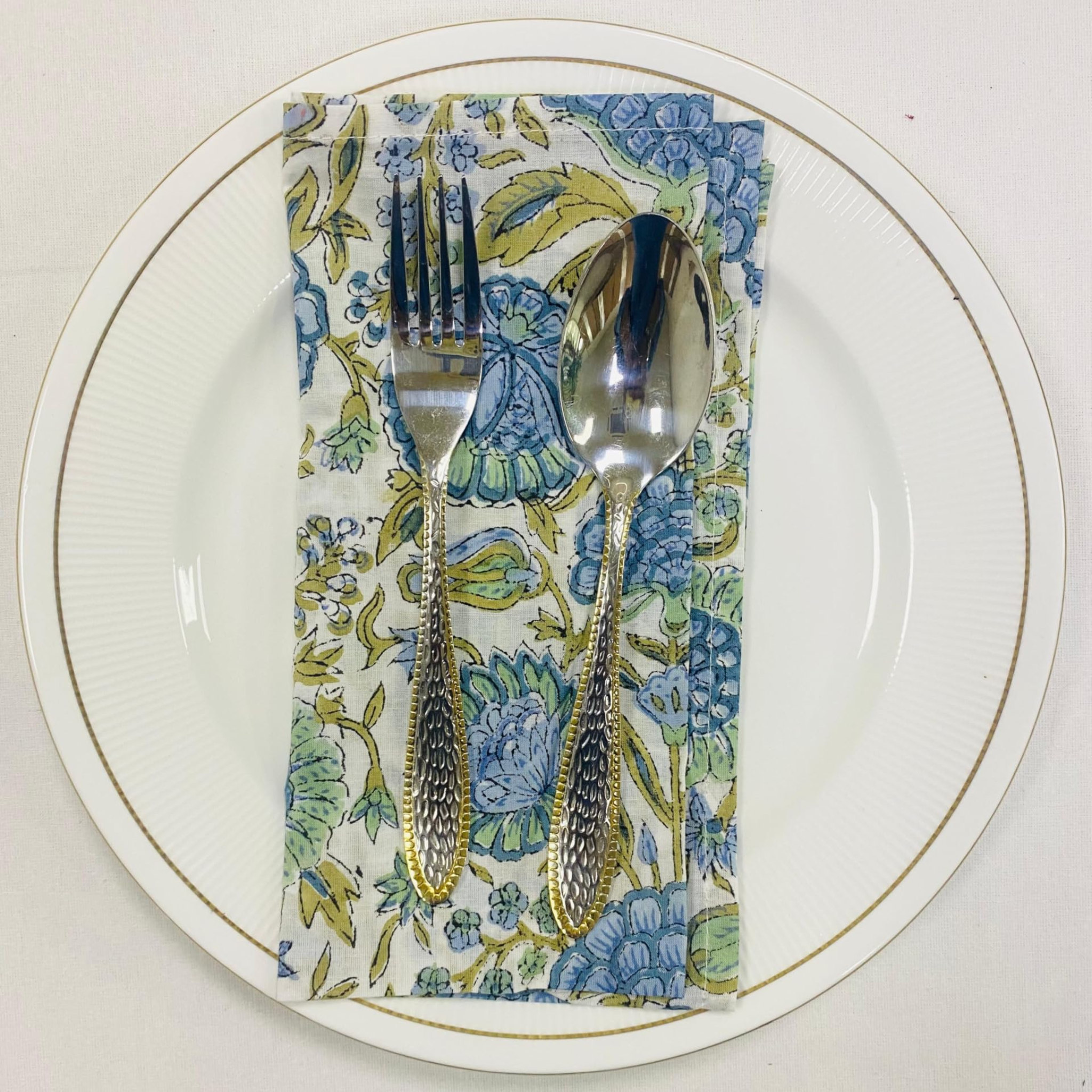 Silverware on a floral napkin with a white plate