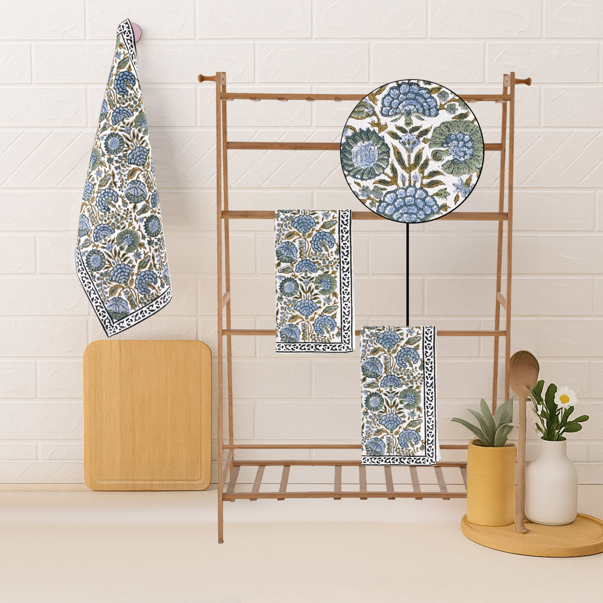 Set of blue and green patterned towels on a wooden rack against a white tiled wall.