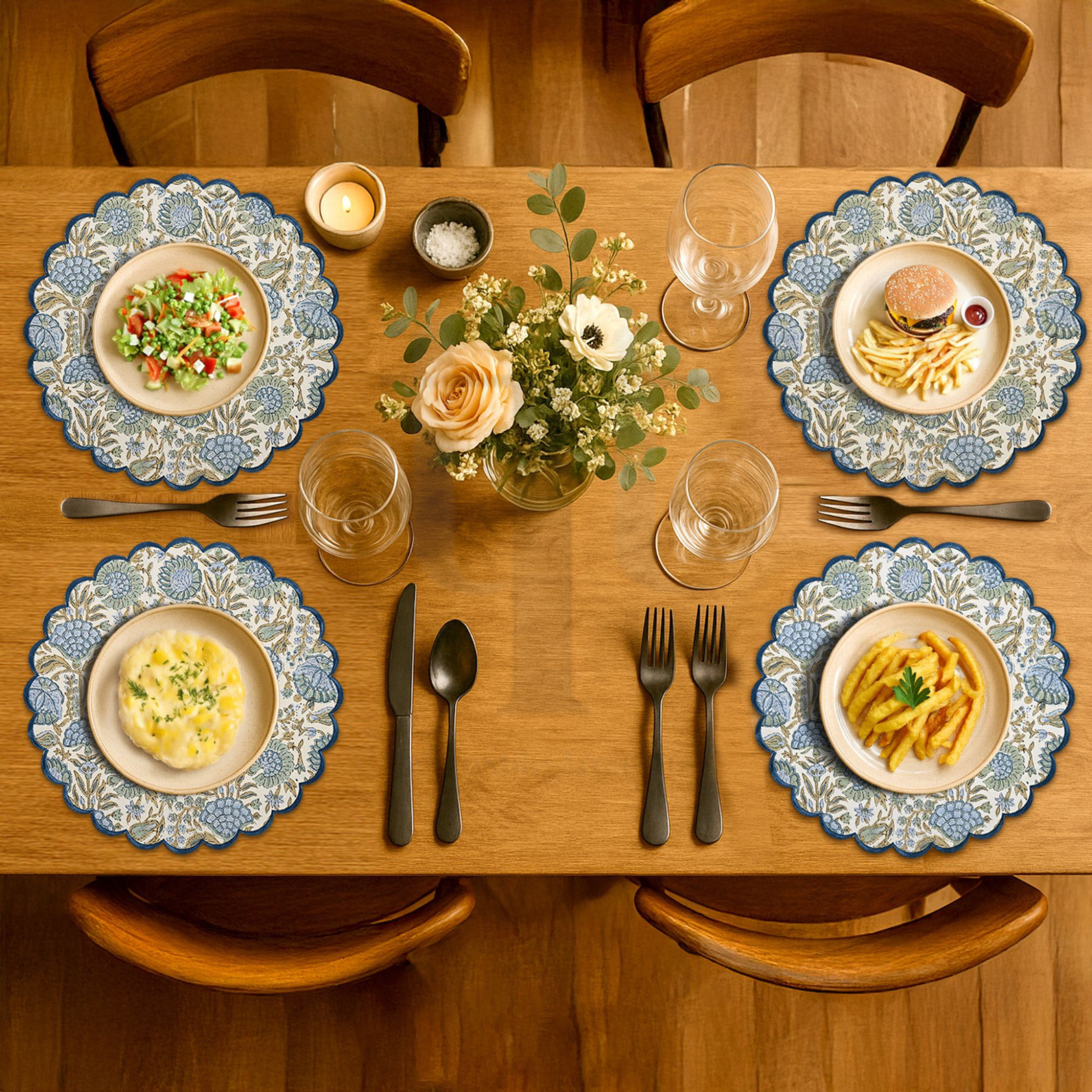 Dining table set with plates of food, glasses, and cutlery on a wooden table.