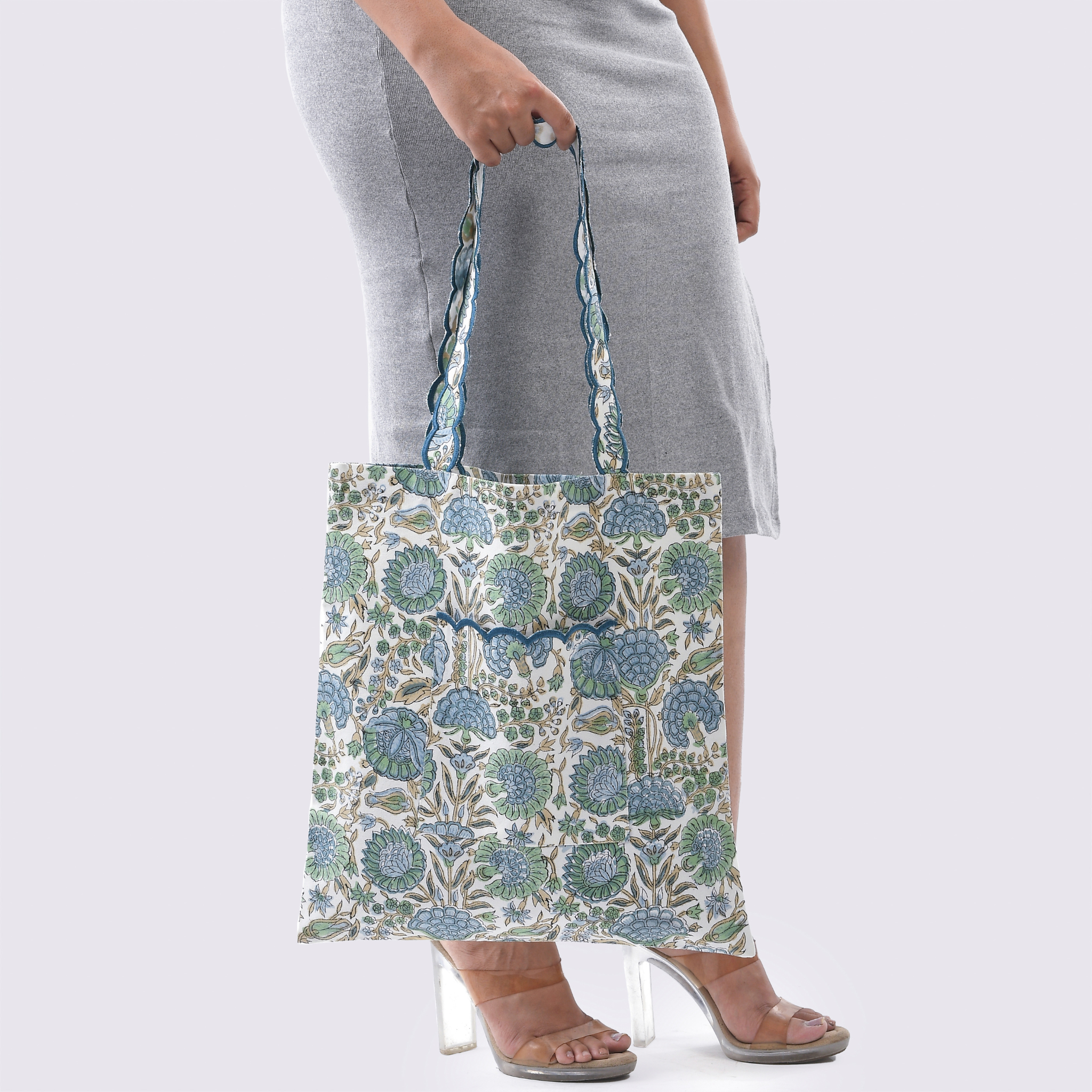 Person holding a floral-patterned tote bag against a plain background