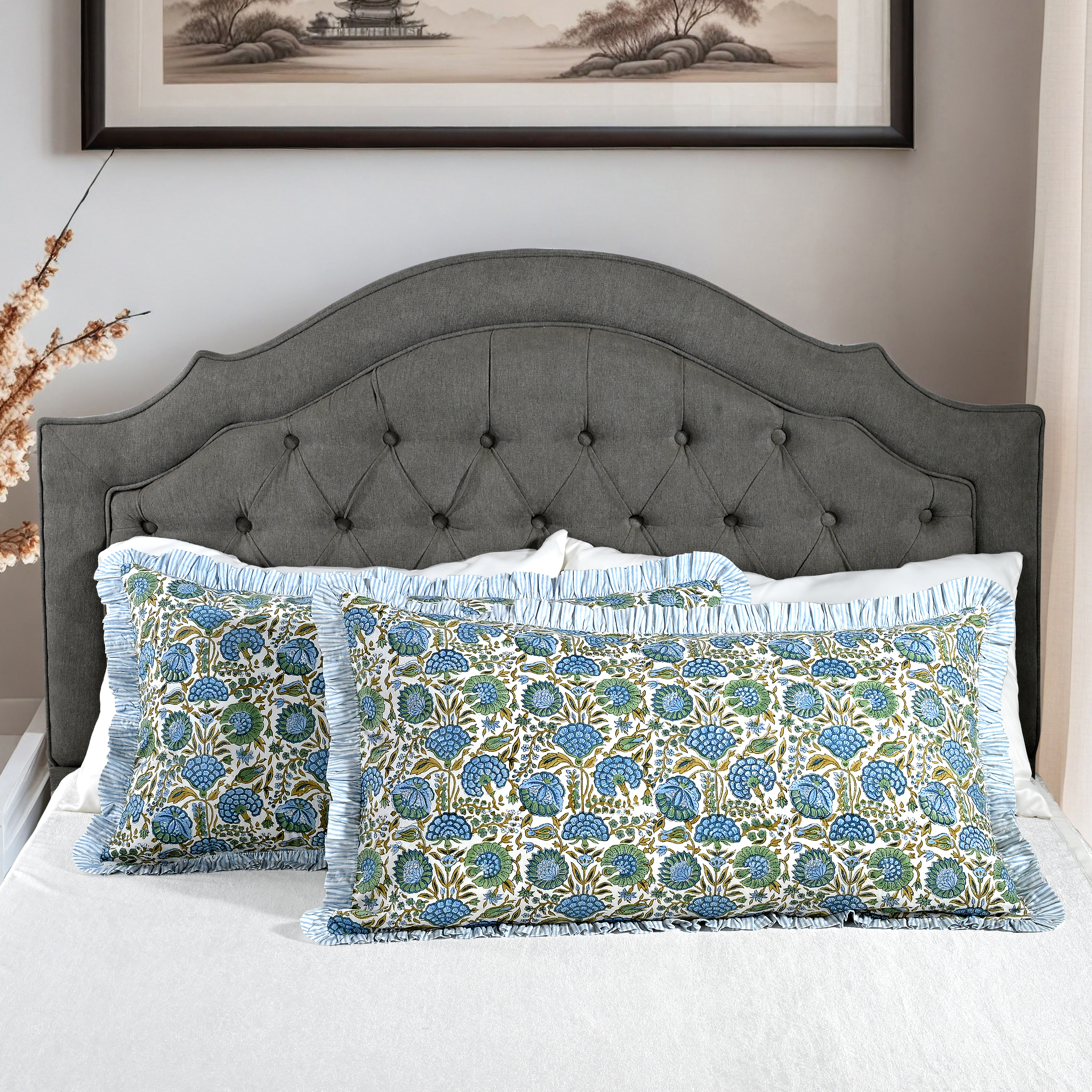 Large block print cotton pillows styled on gray upholstered bed.