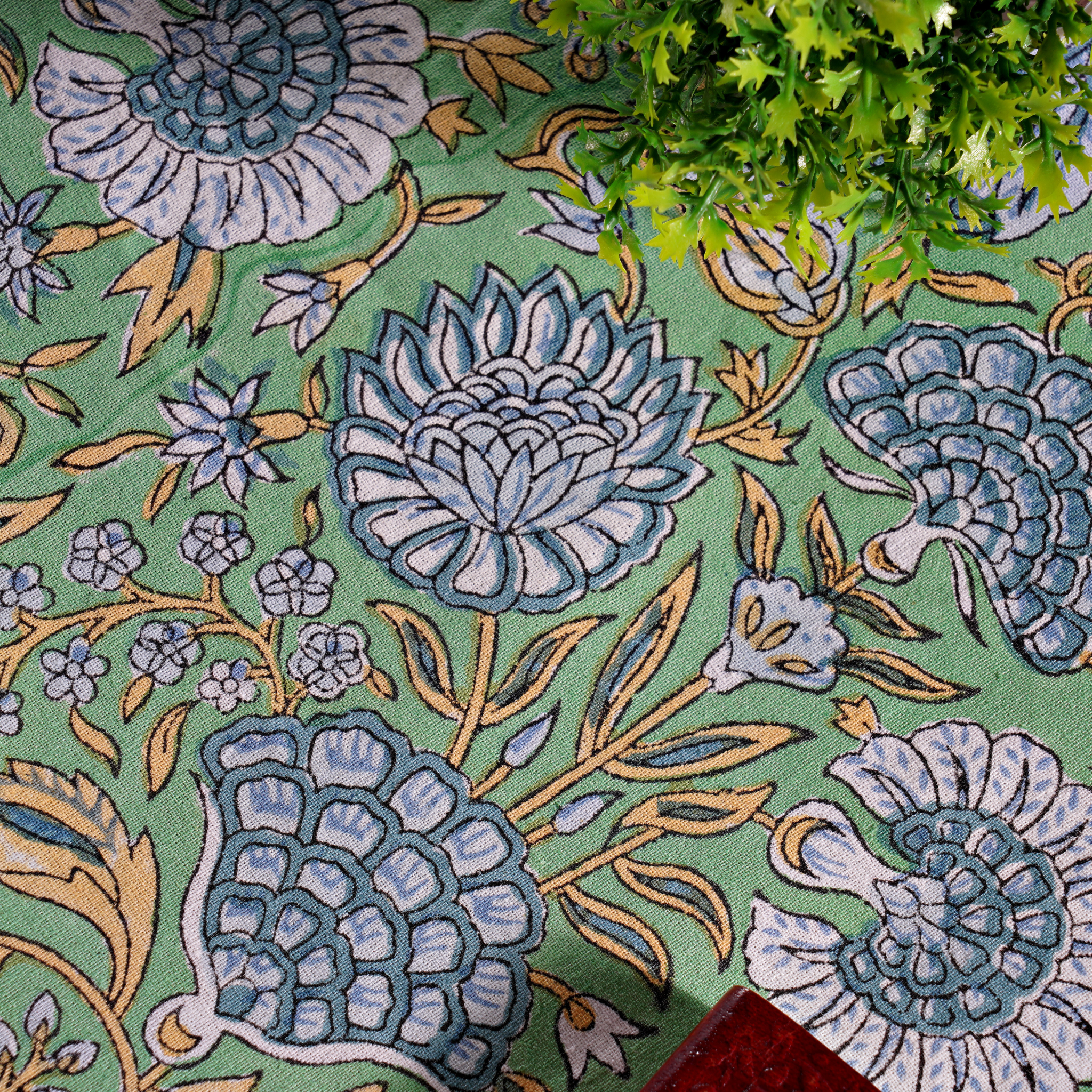 Close-up of a floral patterned rug with blue flowers on a green background.