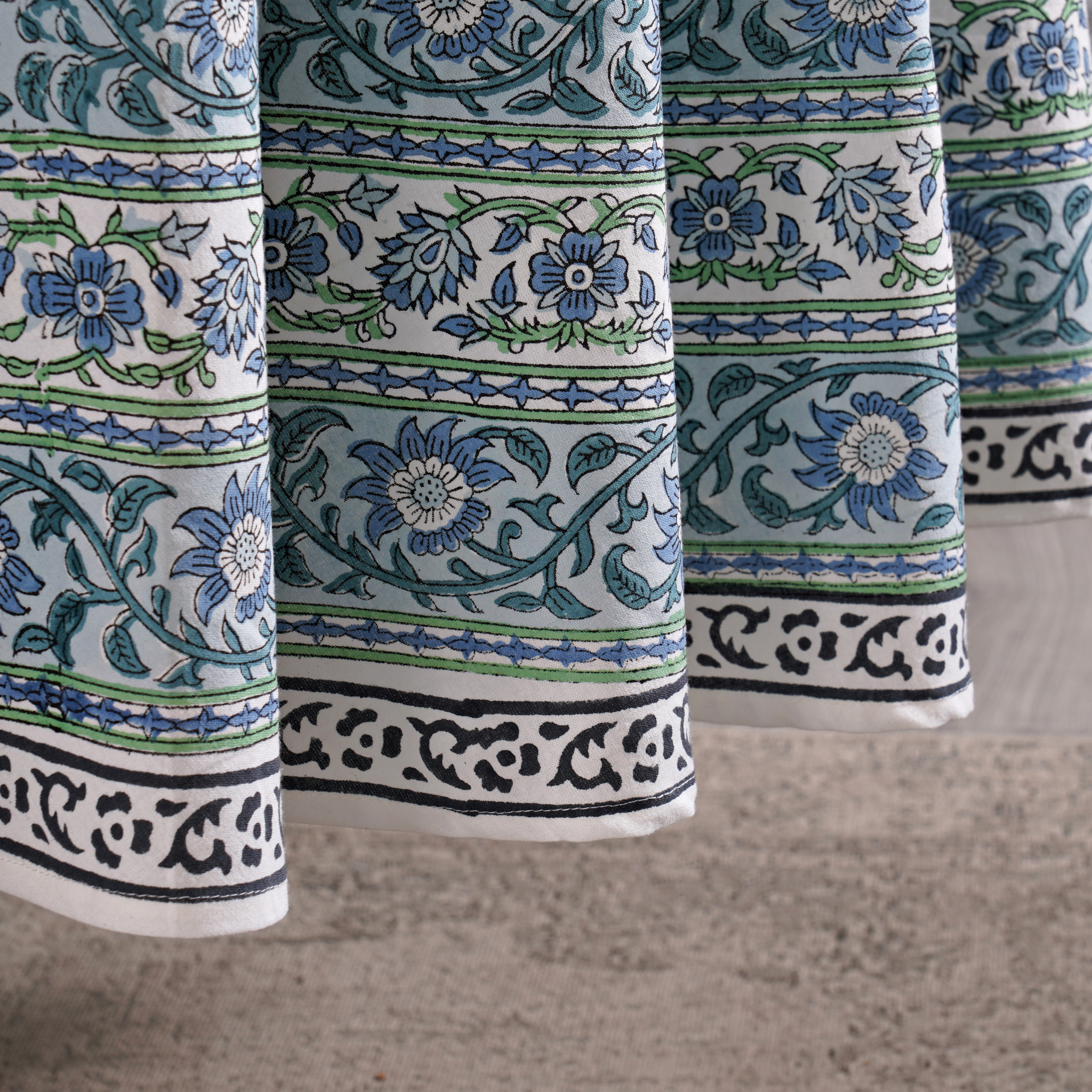Close-up of patterned fabric with blue and green floral designs on a neutral background