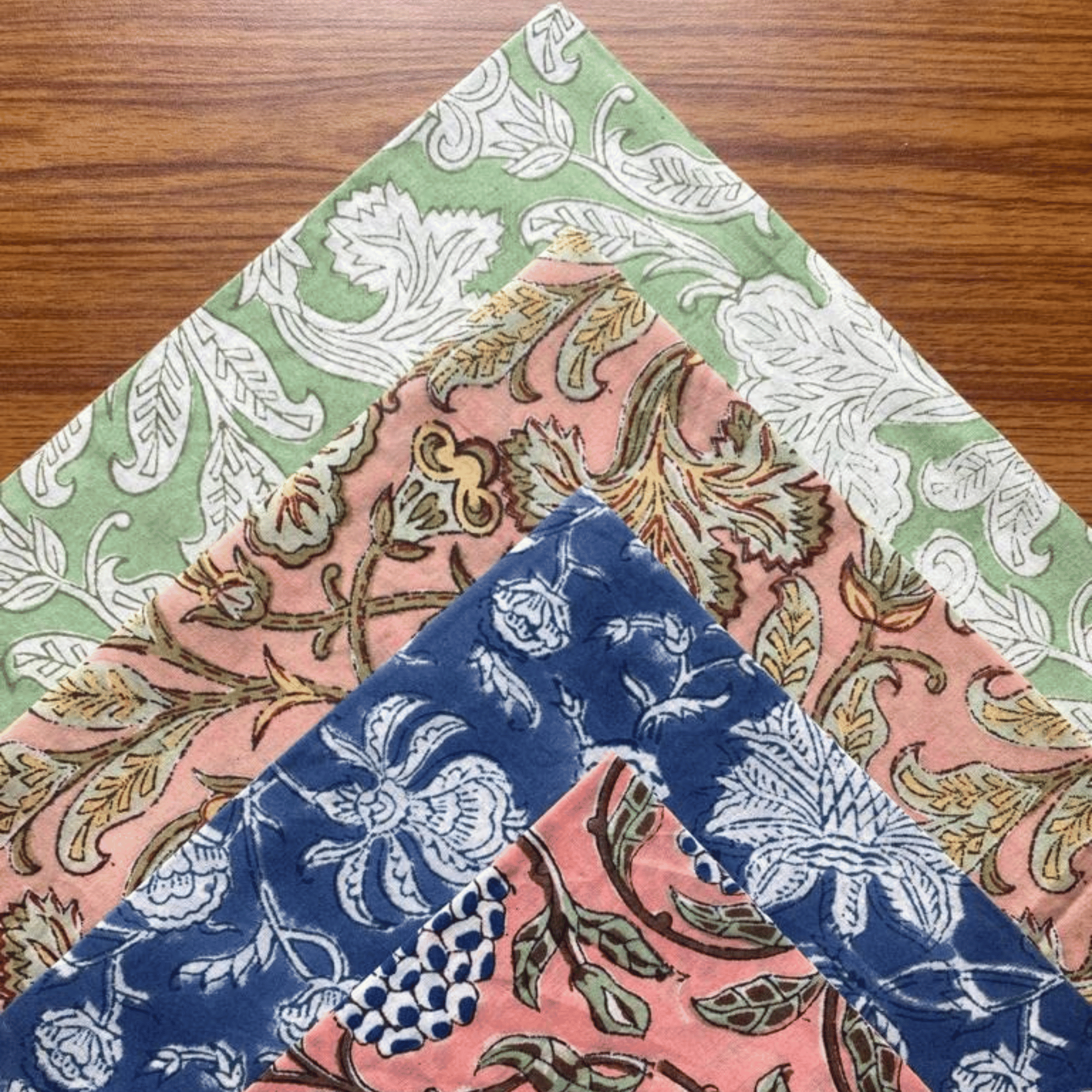 Three floral patterned napkins on a wooden surface