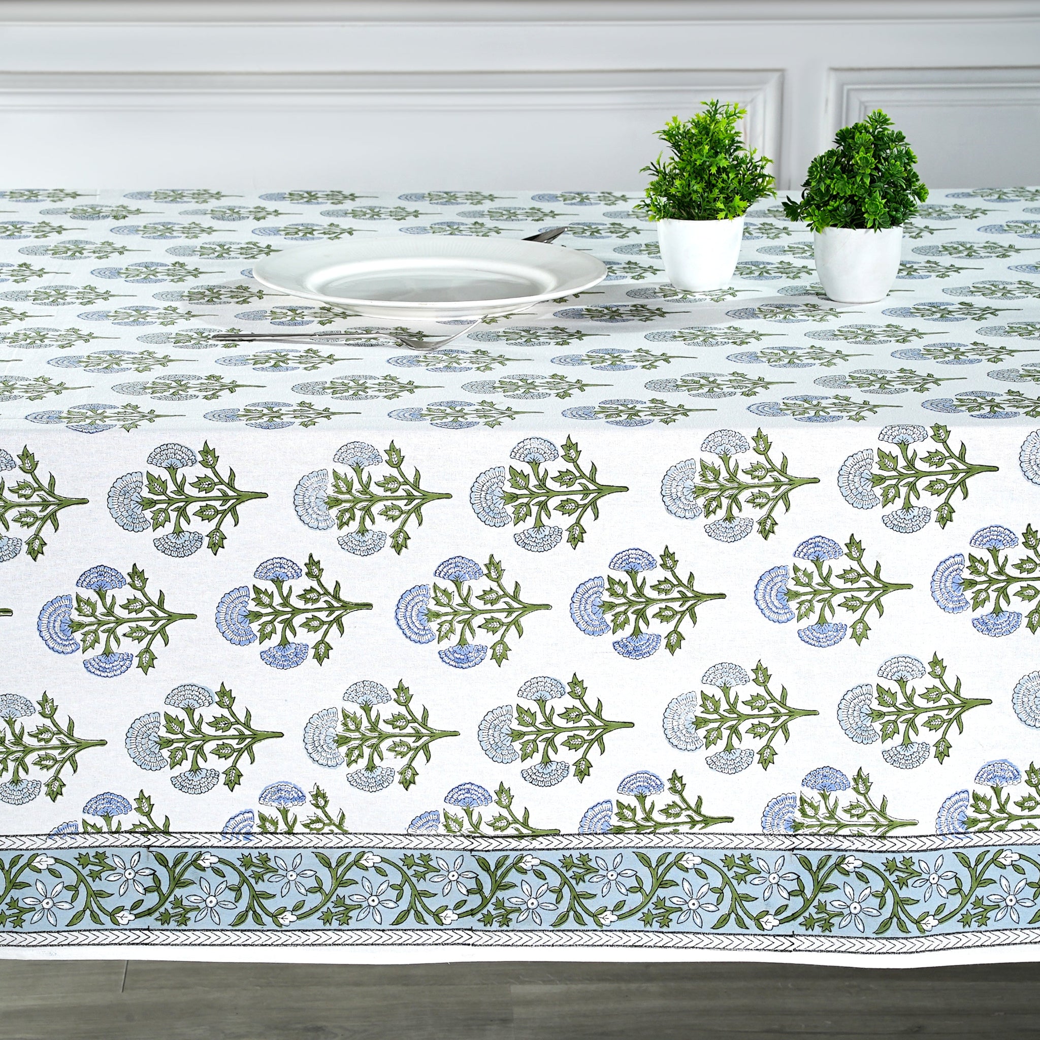 Decorative tablecloth with green and blue patterns on a white table setting.