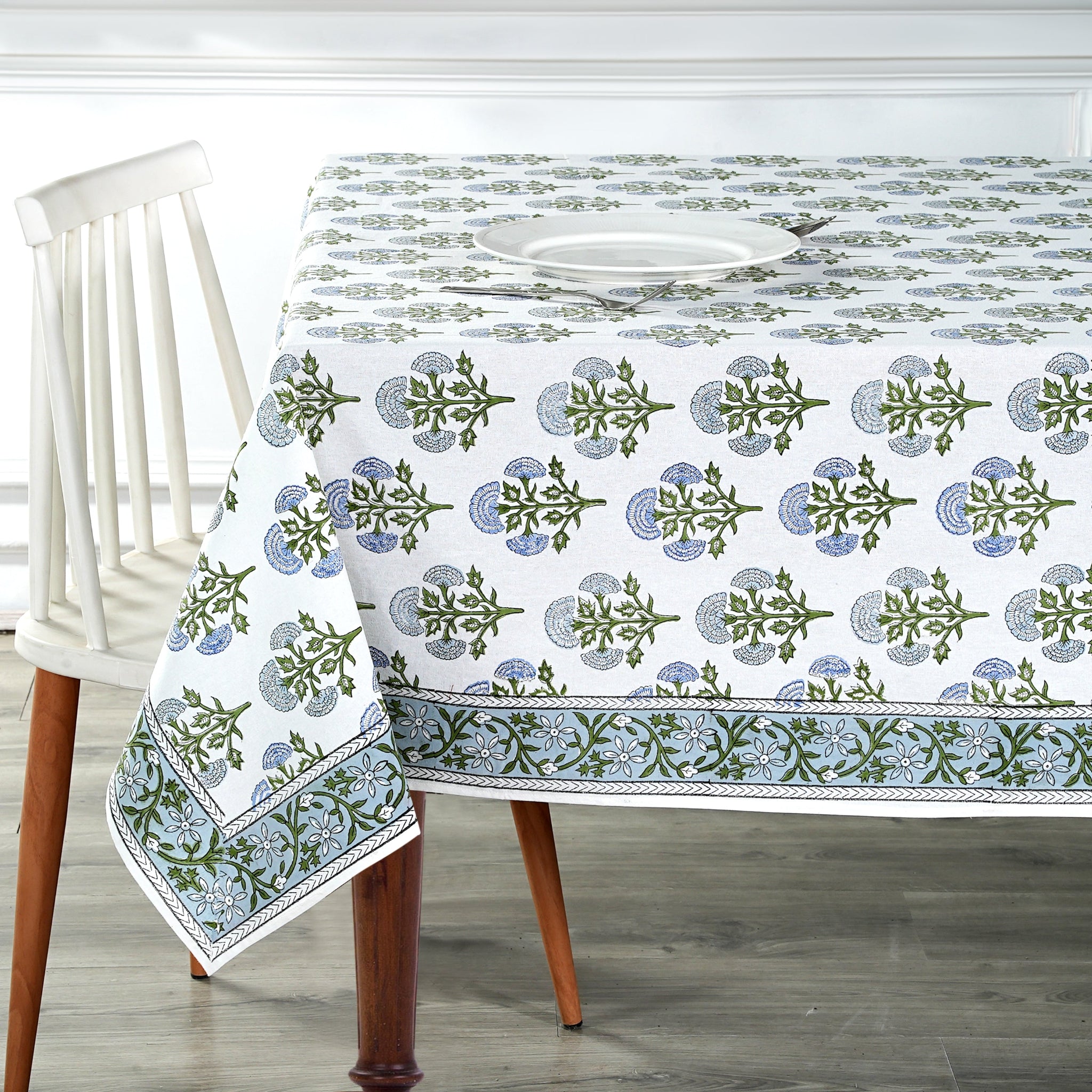 Tablecloth with green and blue floral pattern on a wooden table and chair.