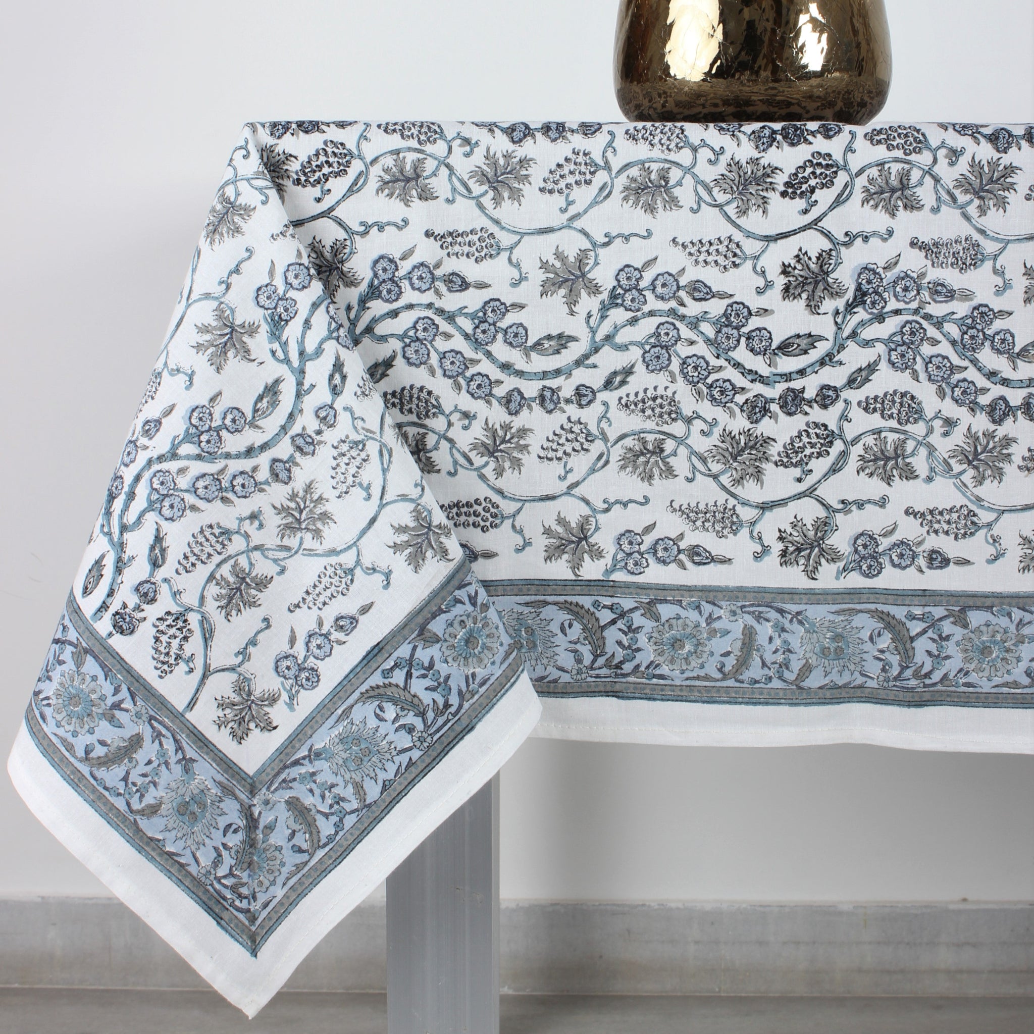 Tablecloth with floral pattern on a table, accompanied by a vase of pink flowers.