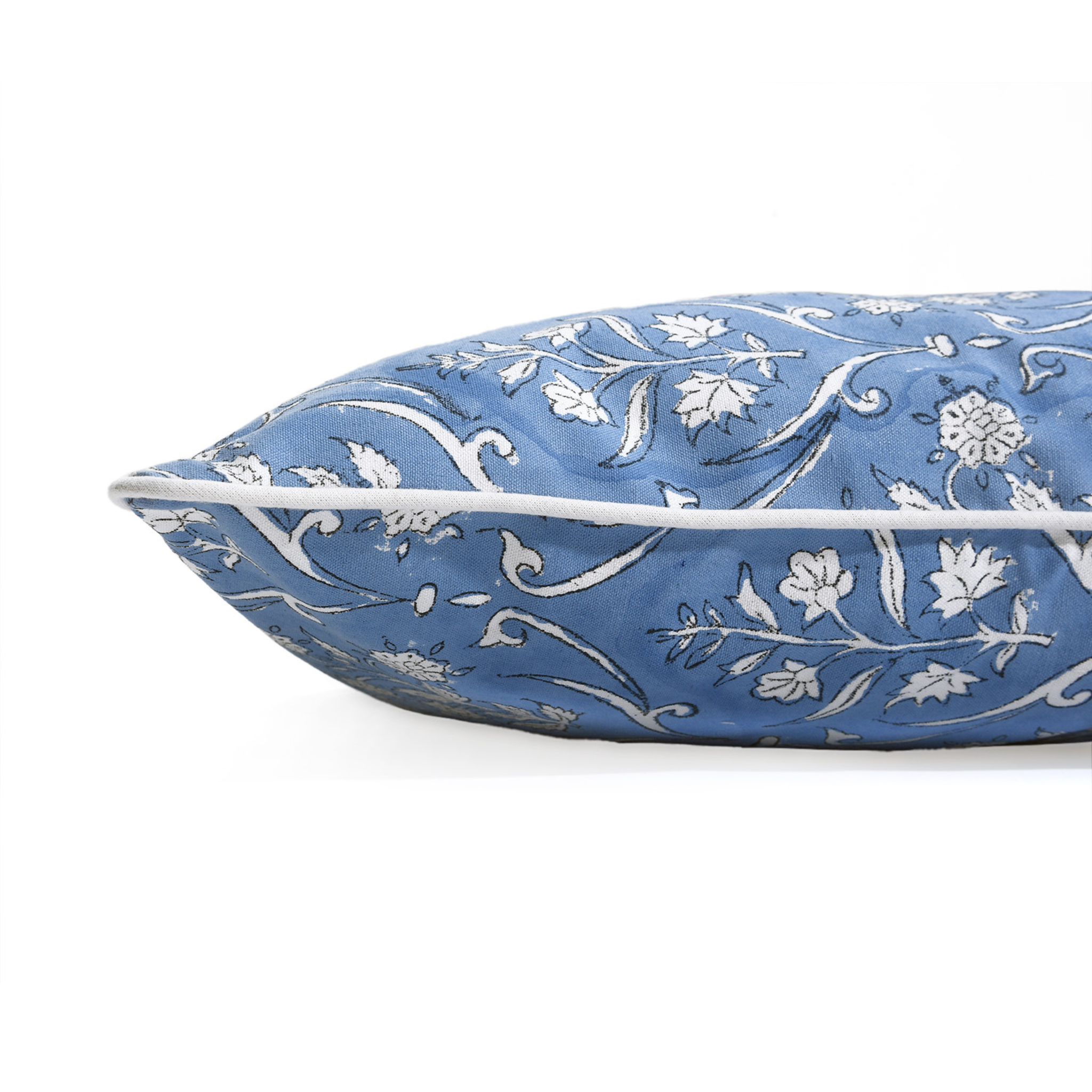 Decorative blue pillow with white floral patterns on a white background