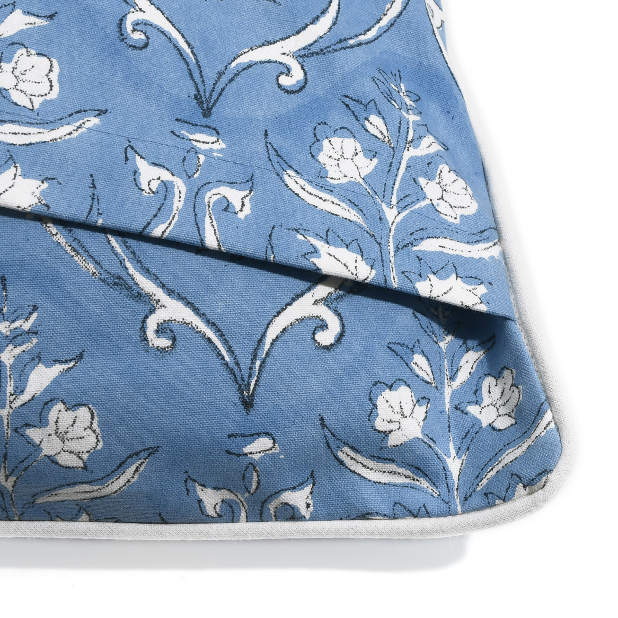 Blue fabric with white floral and leaf pattern on a white background