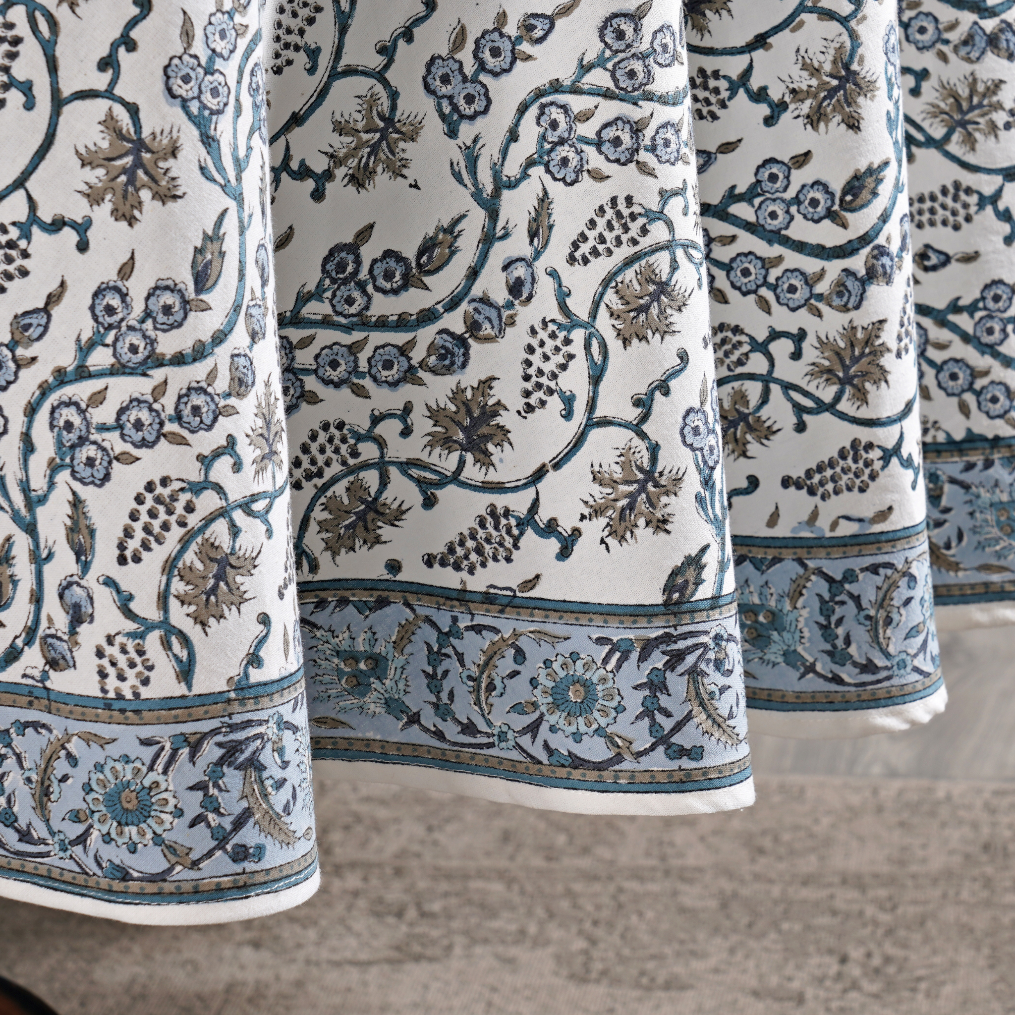 Close-up of patterned fabric with floral and vine designs on a neutral background