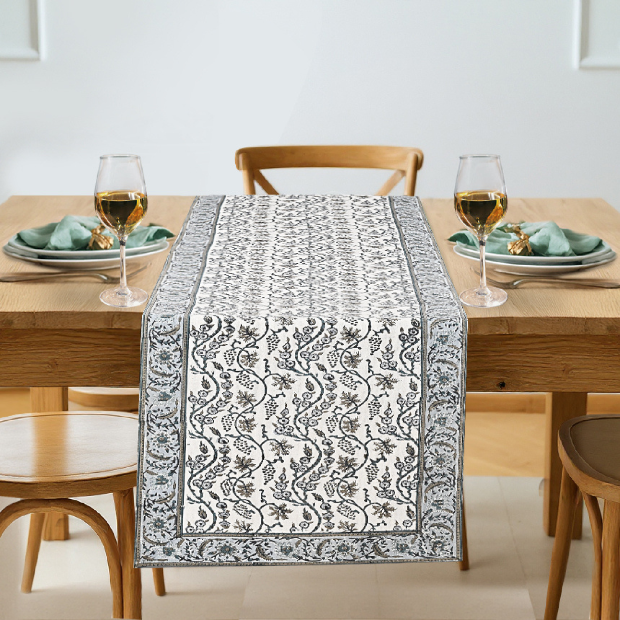 Dining table set with a patterned table runner, glasses, and plates.