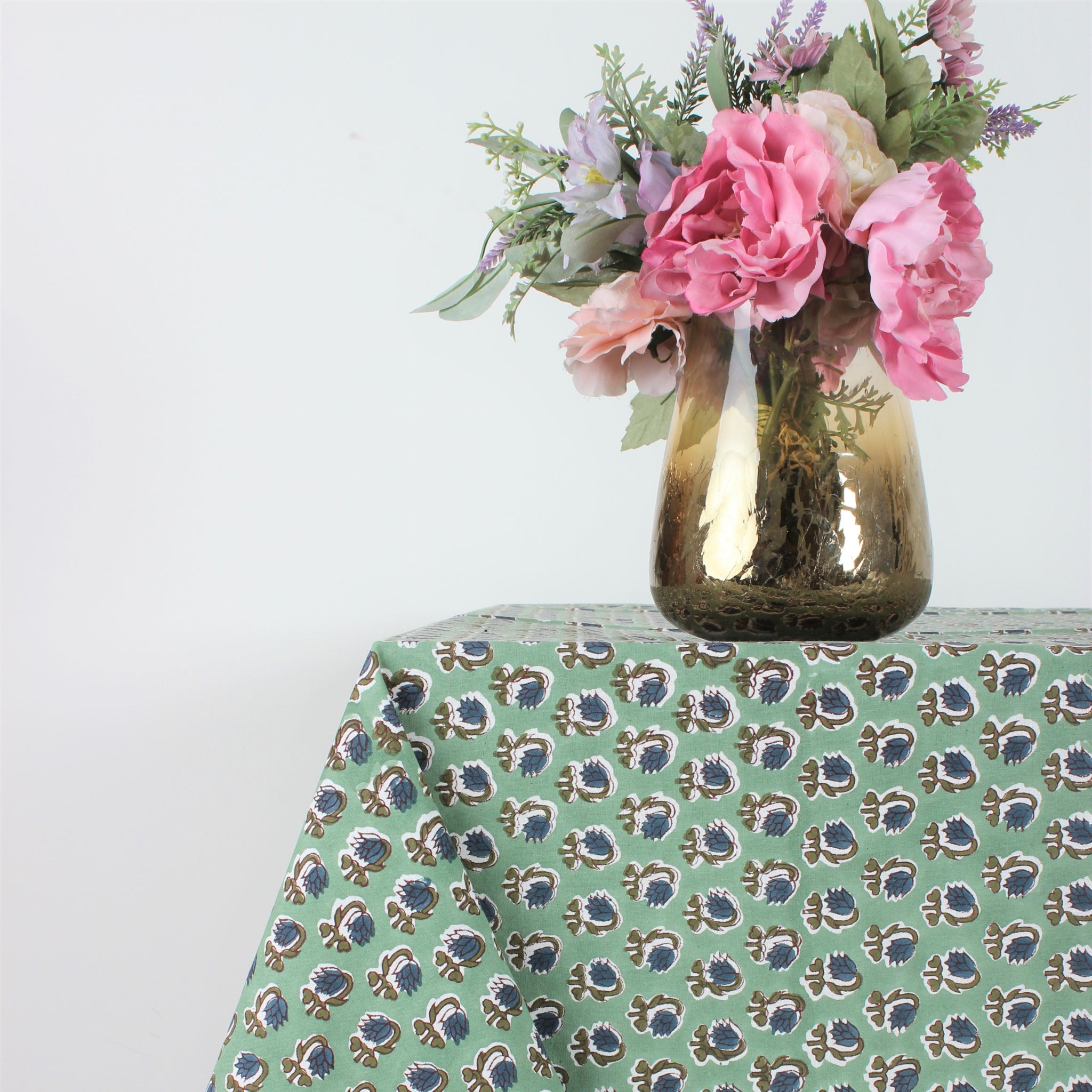 Tablecloth with floral pattern on a table with a vase of flowers.