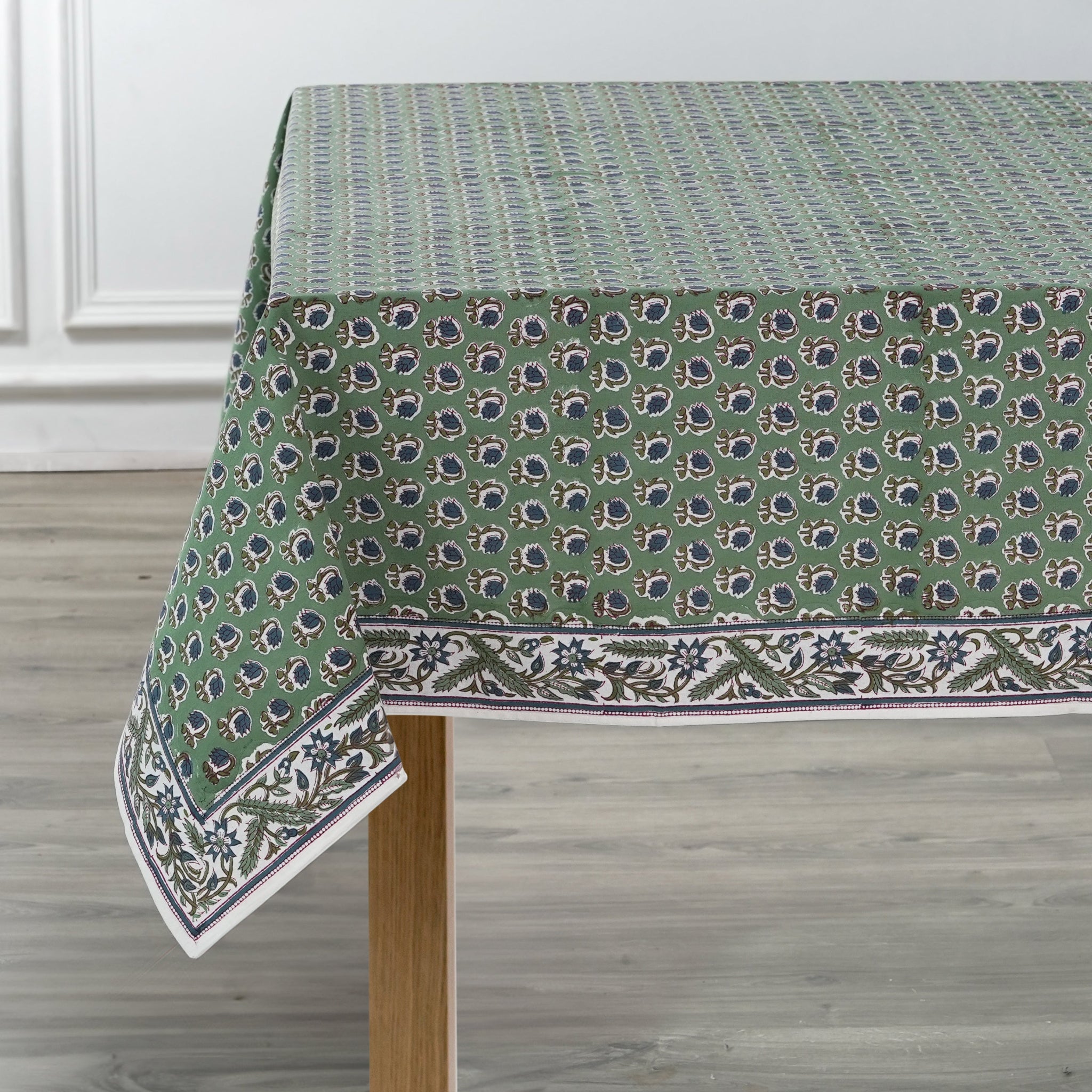 Green patterned tablecloth on a wooden table with a white wall background