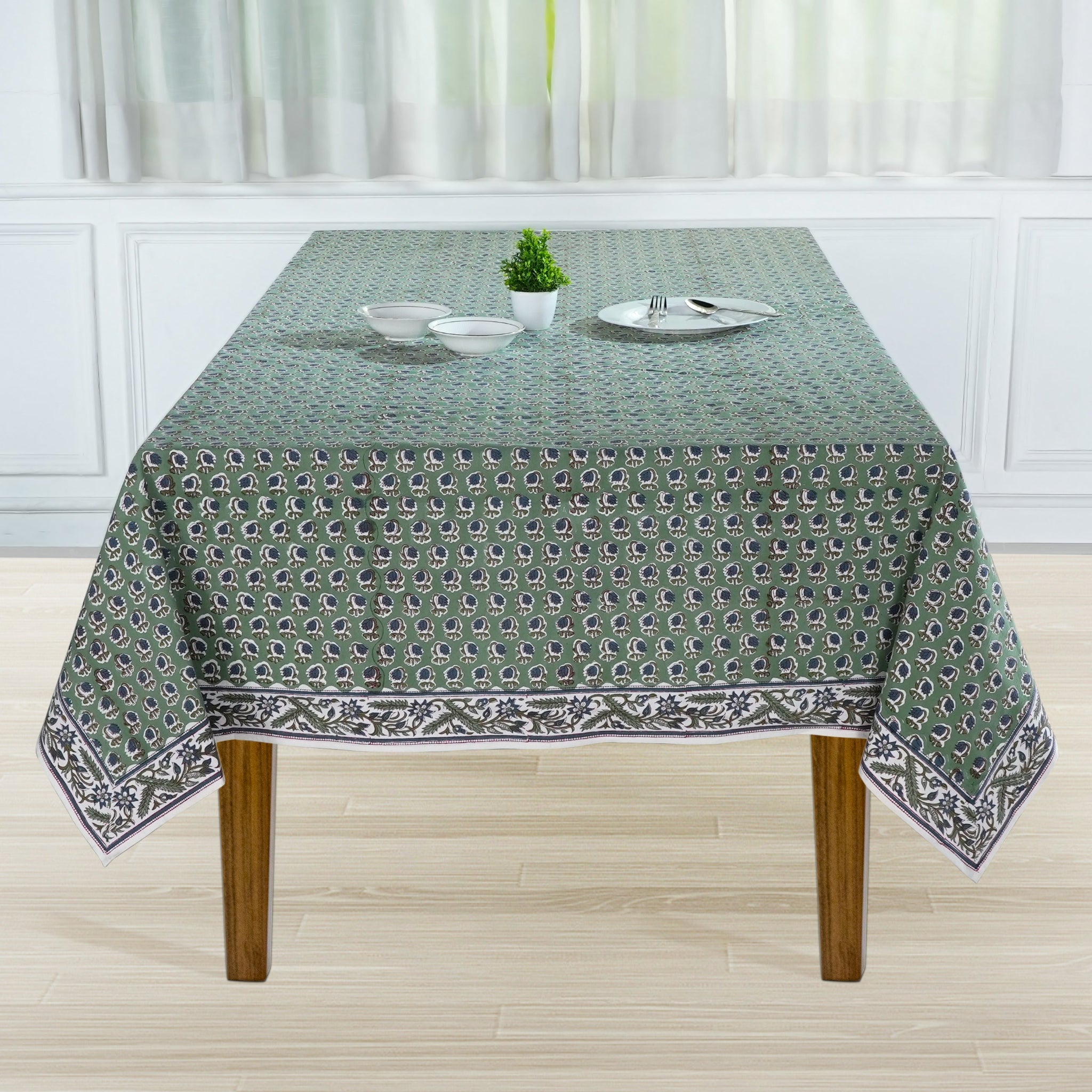 Tablecloth with a pattern on a wooden table in a room with white curtains.