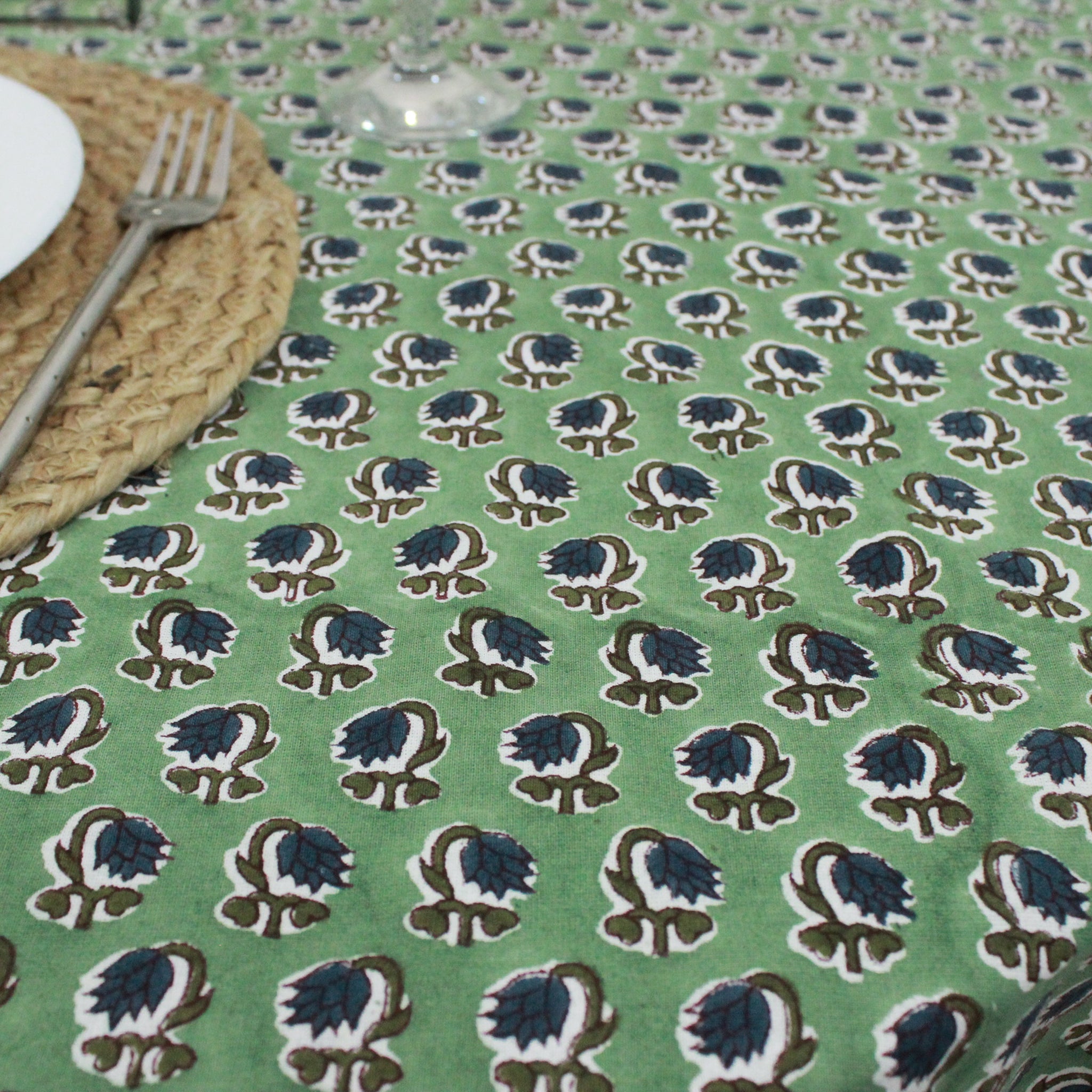 Green tablecloth with a floral pattern on a table setting.