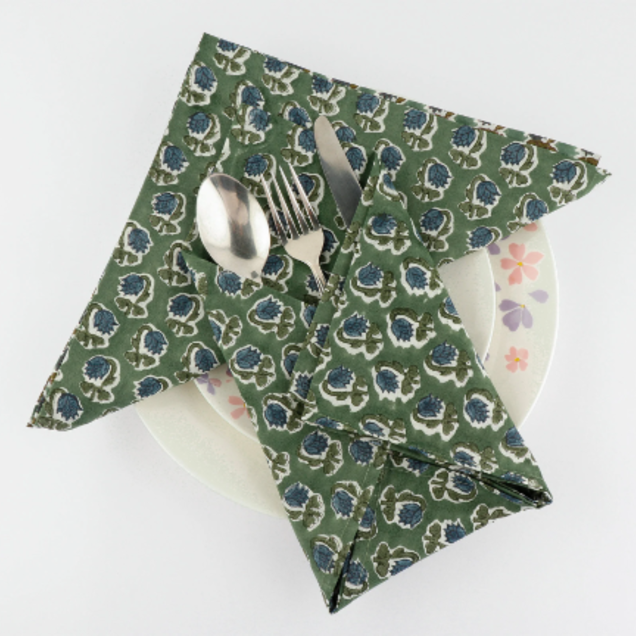 Green patterned napkin with cutlery on a white background