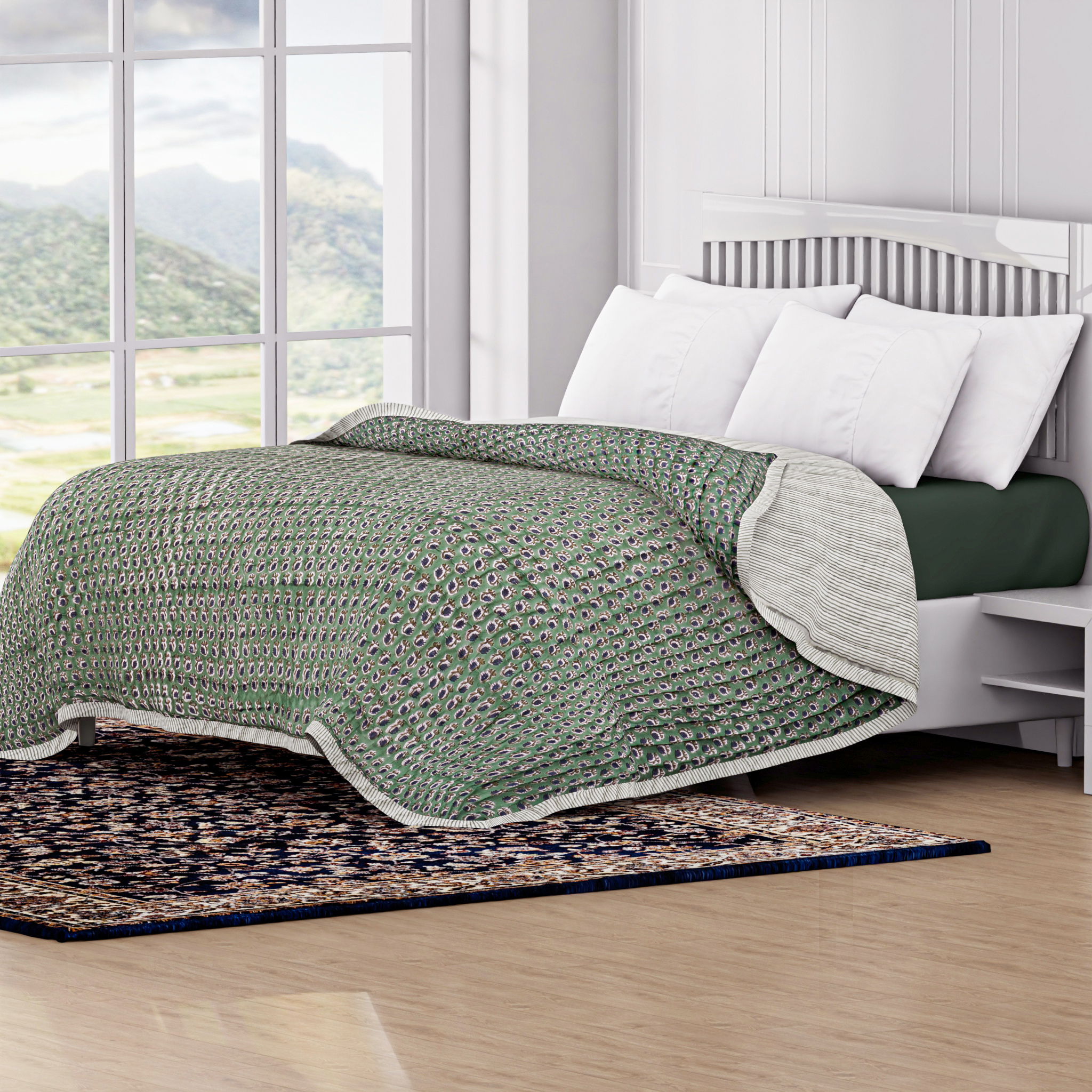 Green and white quilt on a bed with a scenic window view