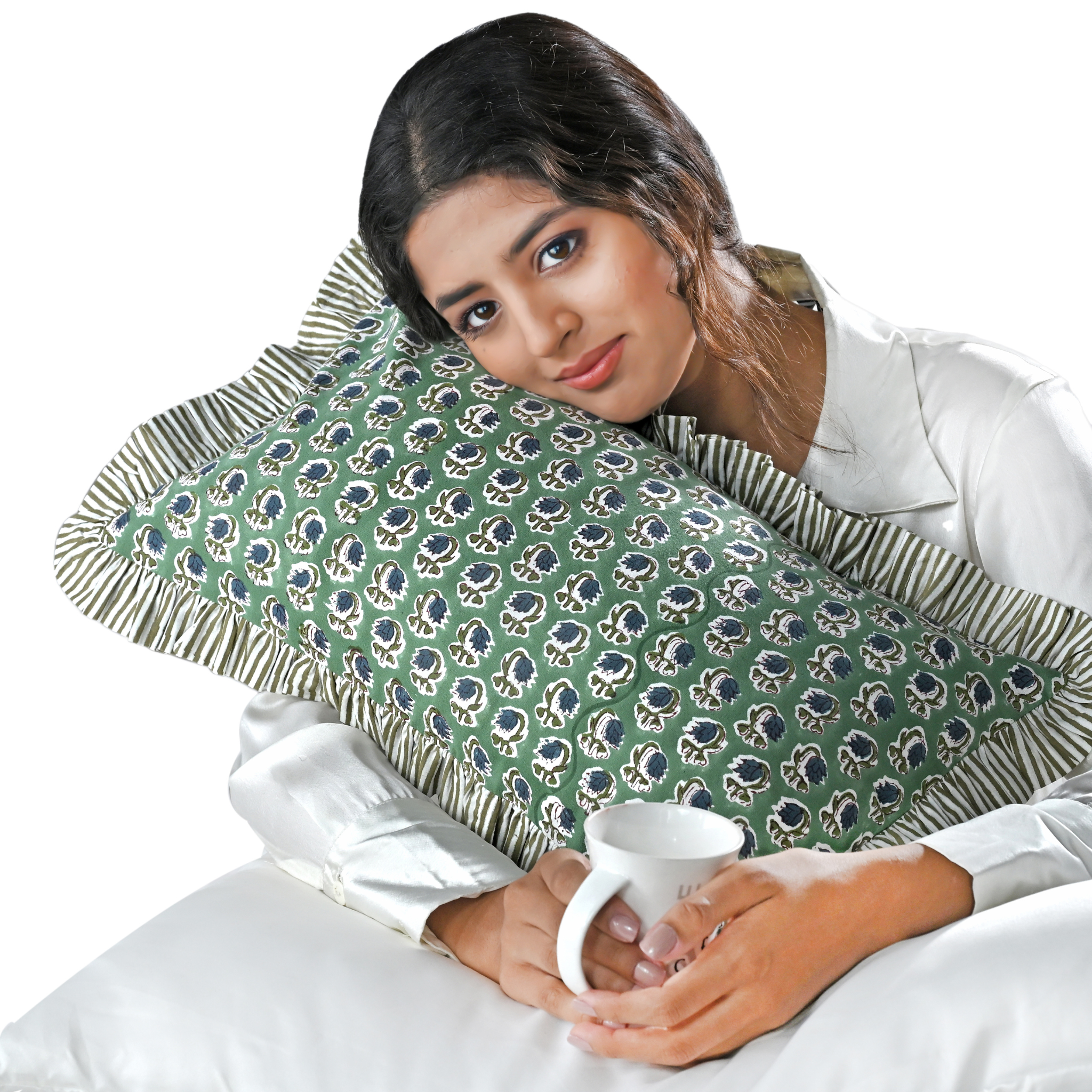 Woman holding a mug with a green patterned pillow behind her head on a white background