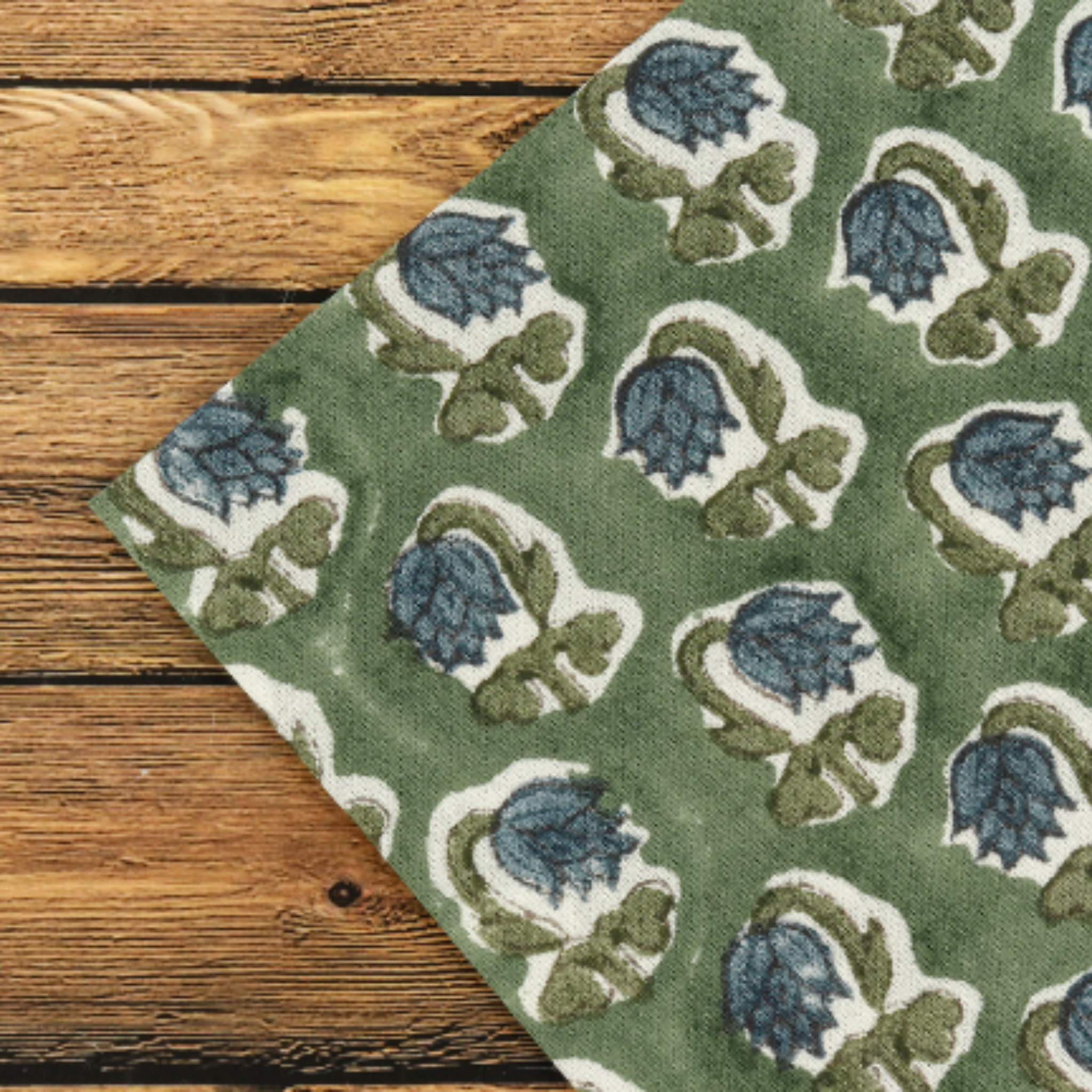 Green fabric with blue and white floral pattern on a wooden surface