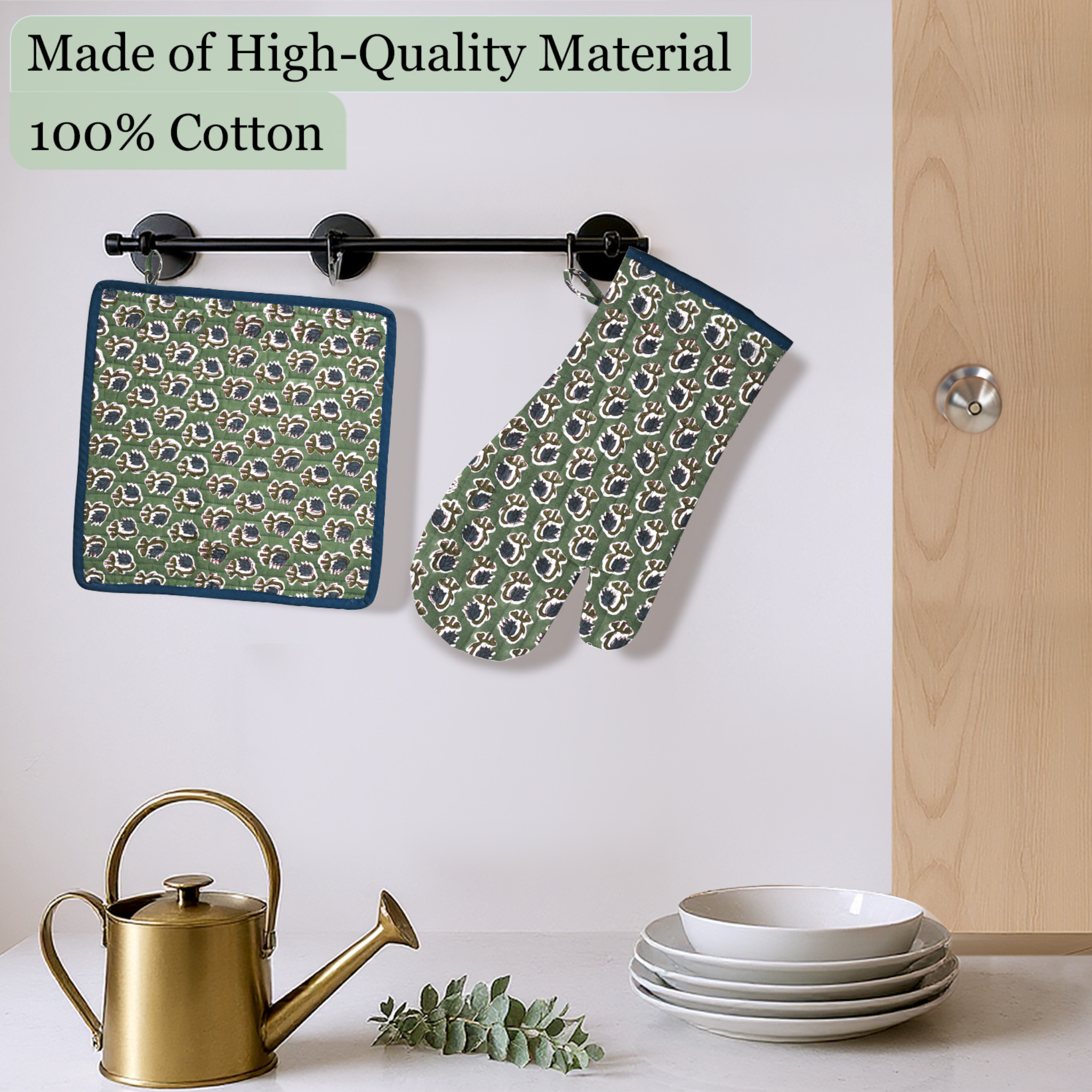 Green patterned pot holder and oven mitt hanging on a rack with kitchen items below.