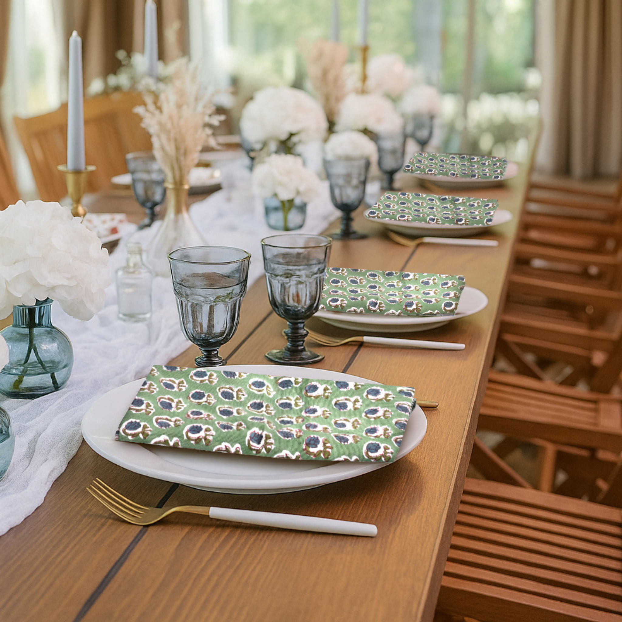 Dining table set with floral plates, glasses, and cutlery in a bright room.
