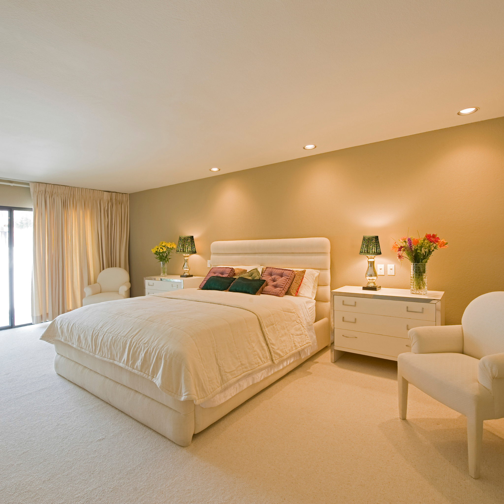 Neatly arranged bedroom with a bed, nightstands, and chairs.