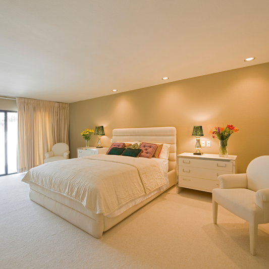 Neatly arranged bedroom with a bed, nightstands, and chairs.