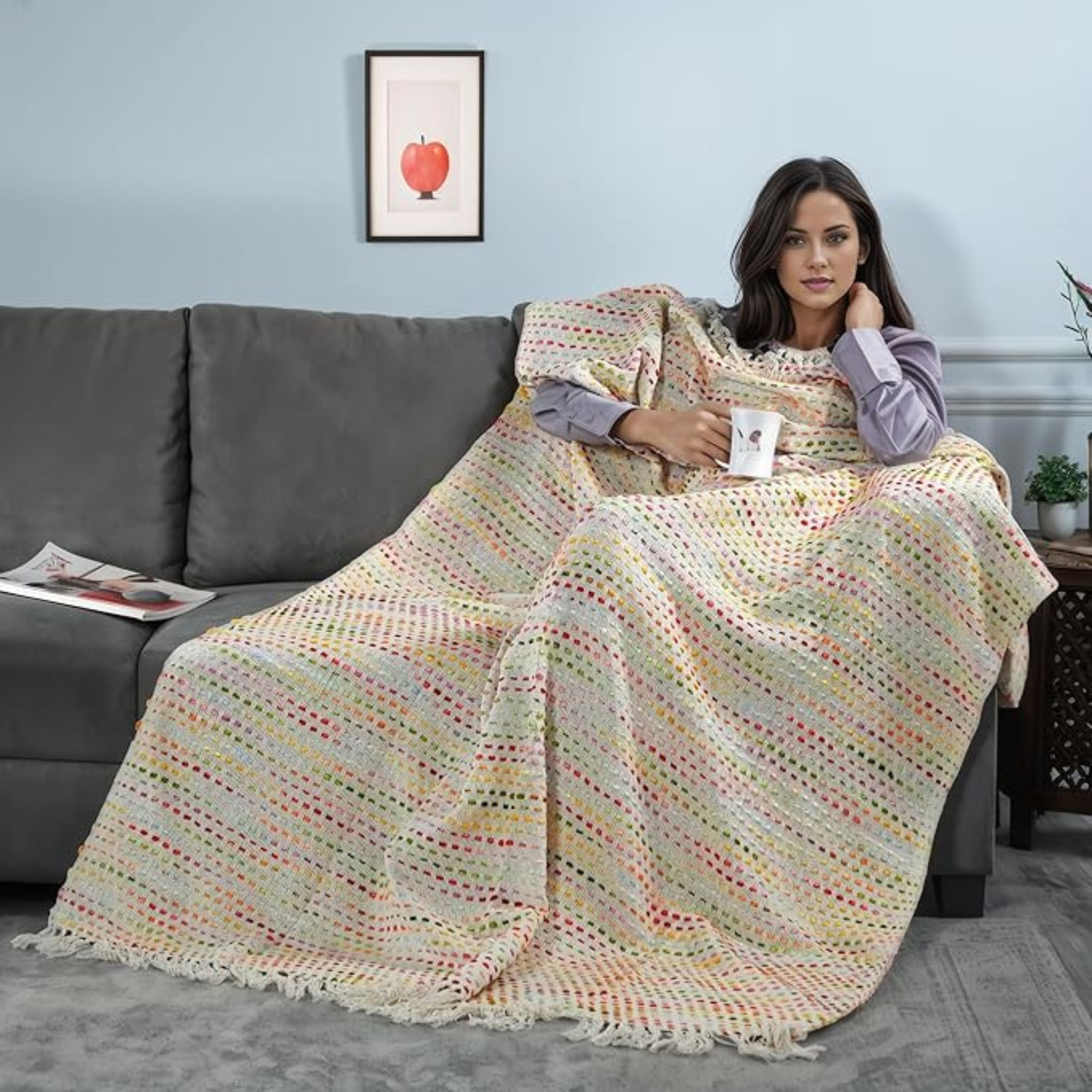 Woman sitting on a couch with a colorful blanket, holding a mug.